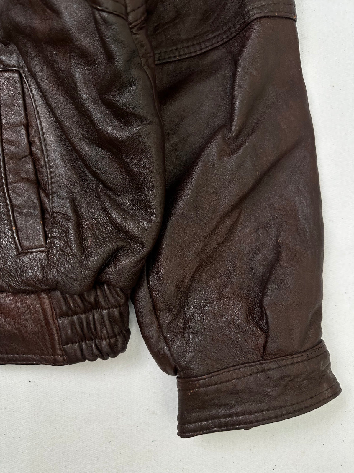 Side pocket and hem of the size L burgundy leather flight jacket, up close