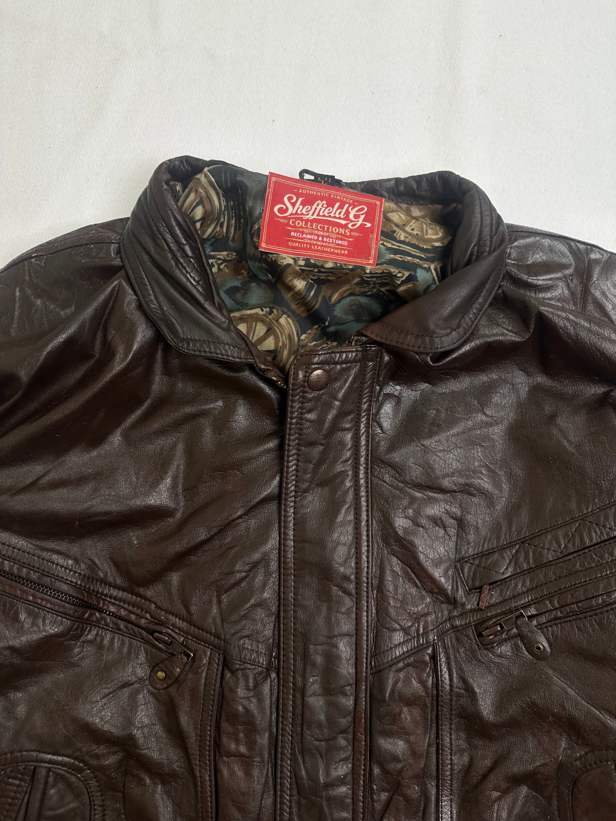 Pointed collar and its throat snap at the top of the zip on this brown blouson