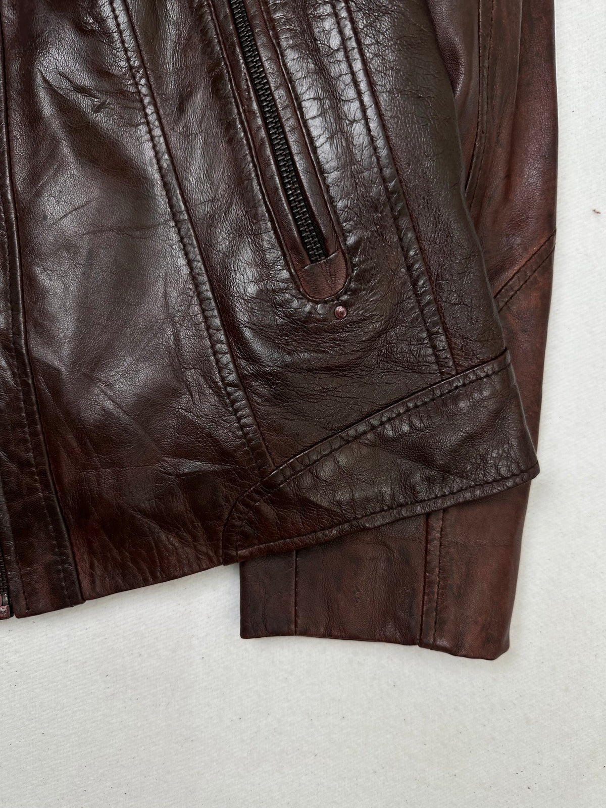 Side pocket and hem of the size S burgundy leather vintage jacket, up close