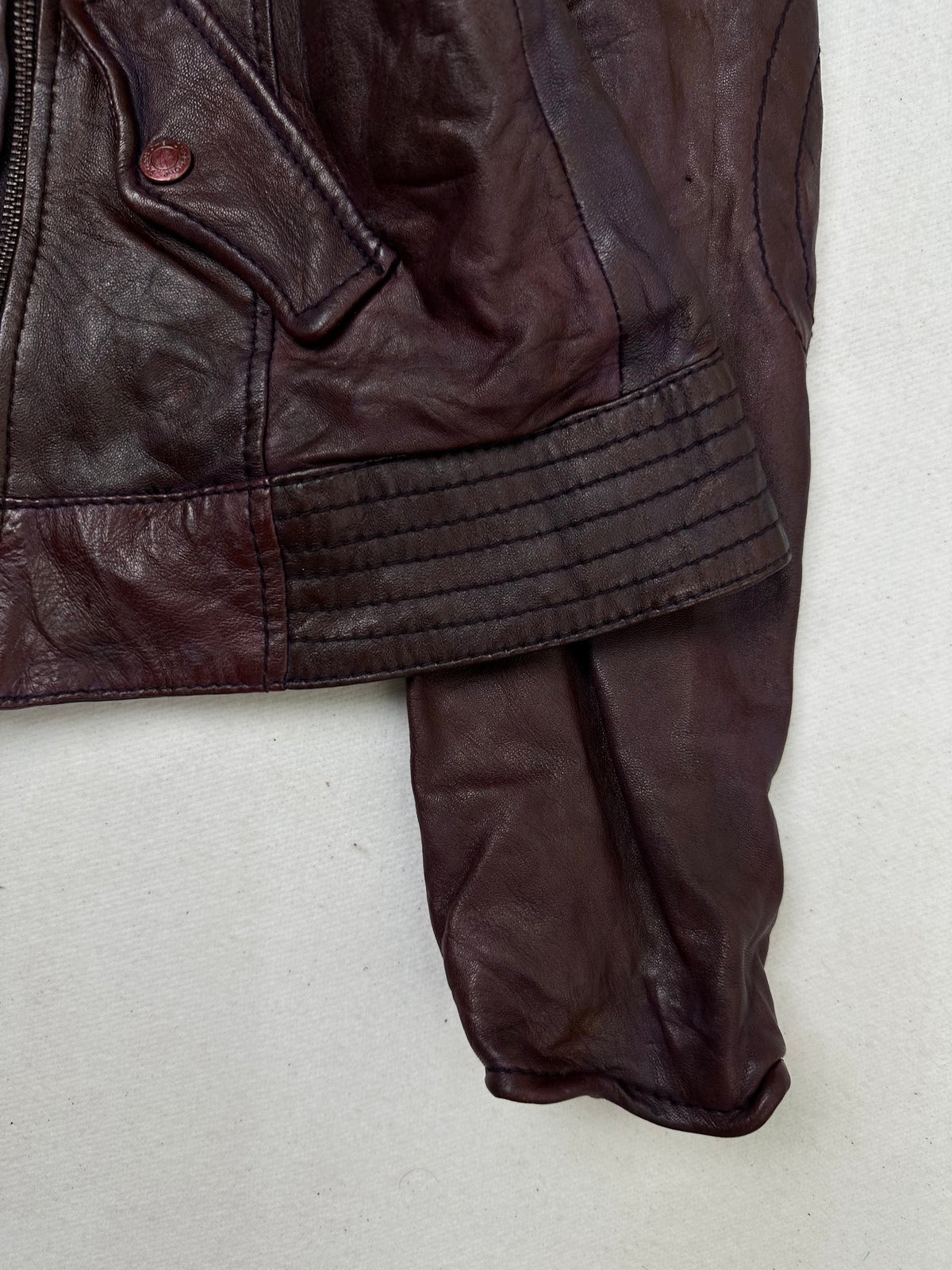 Side pocket and hem of the size S burgundy leather biker jacket, up close