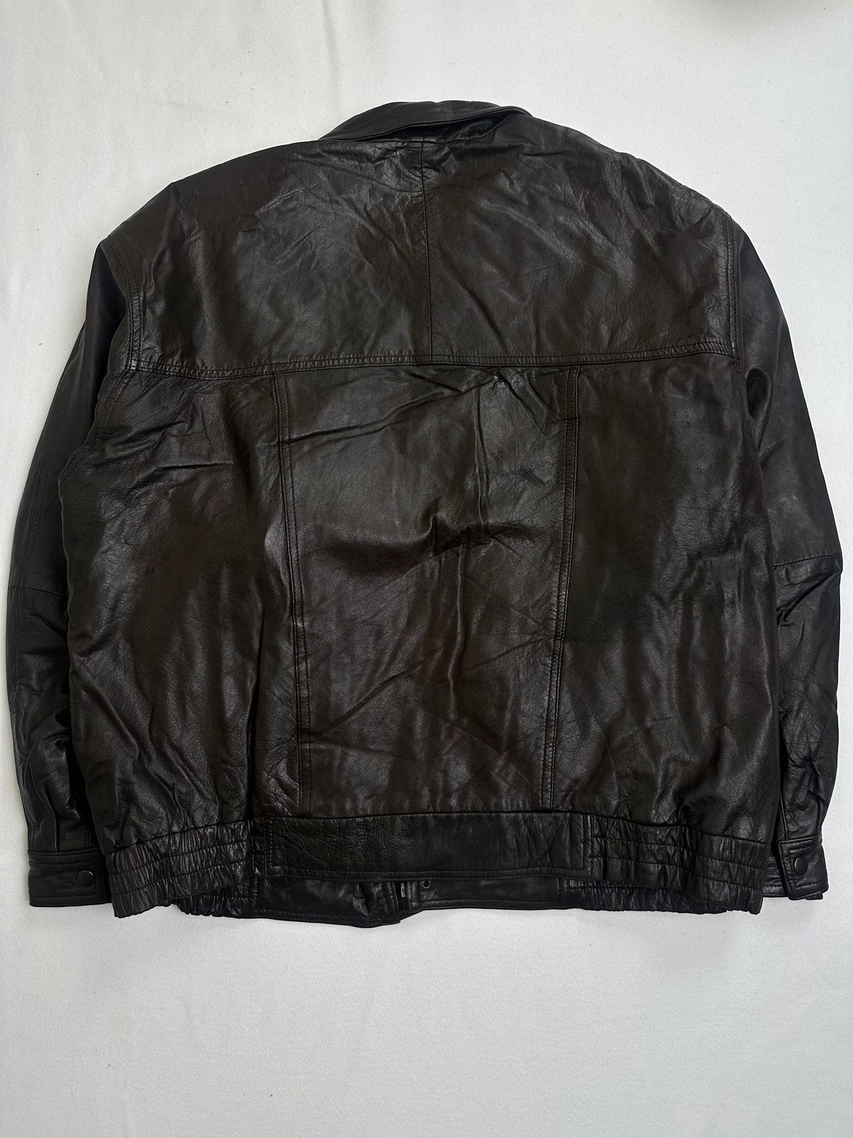 Pointed collar snapping at the throat above the centre zip on the brown harrington