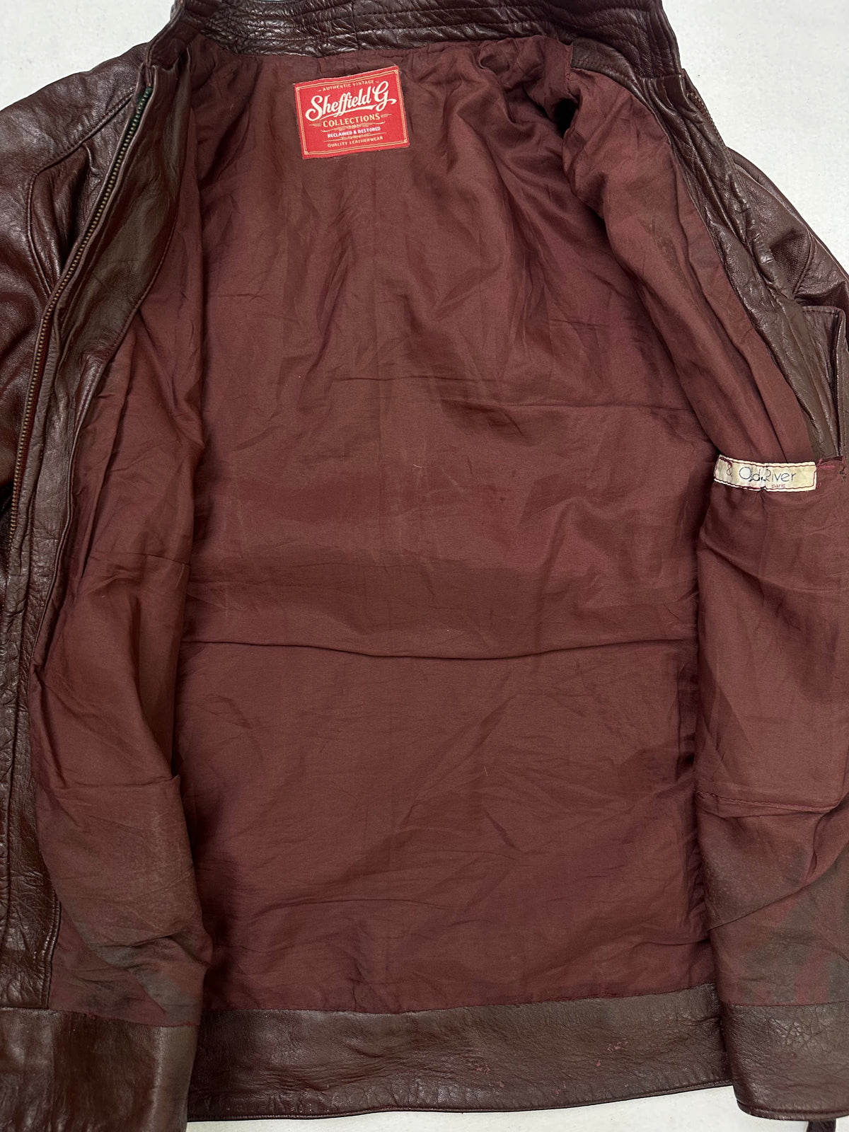 The size L burgundy leather cafe racer jacket opened to show the lining