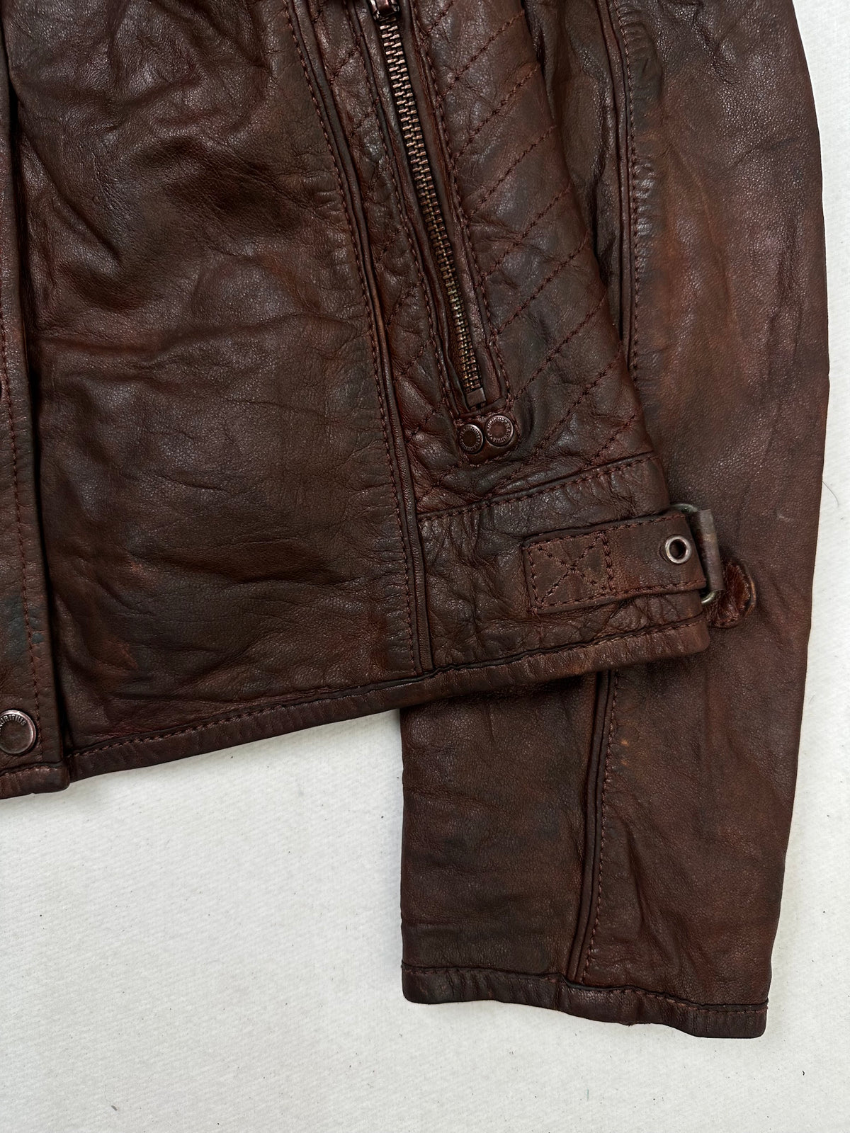 Side pocket and hem of the size S burgundy leather cafe racer jacket, up close