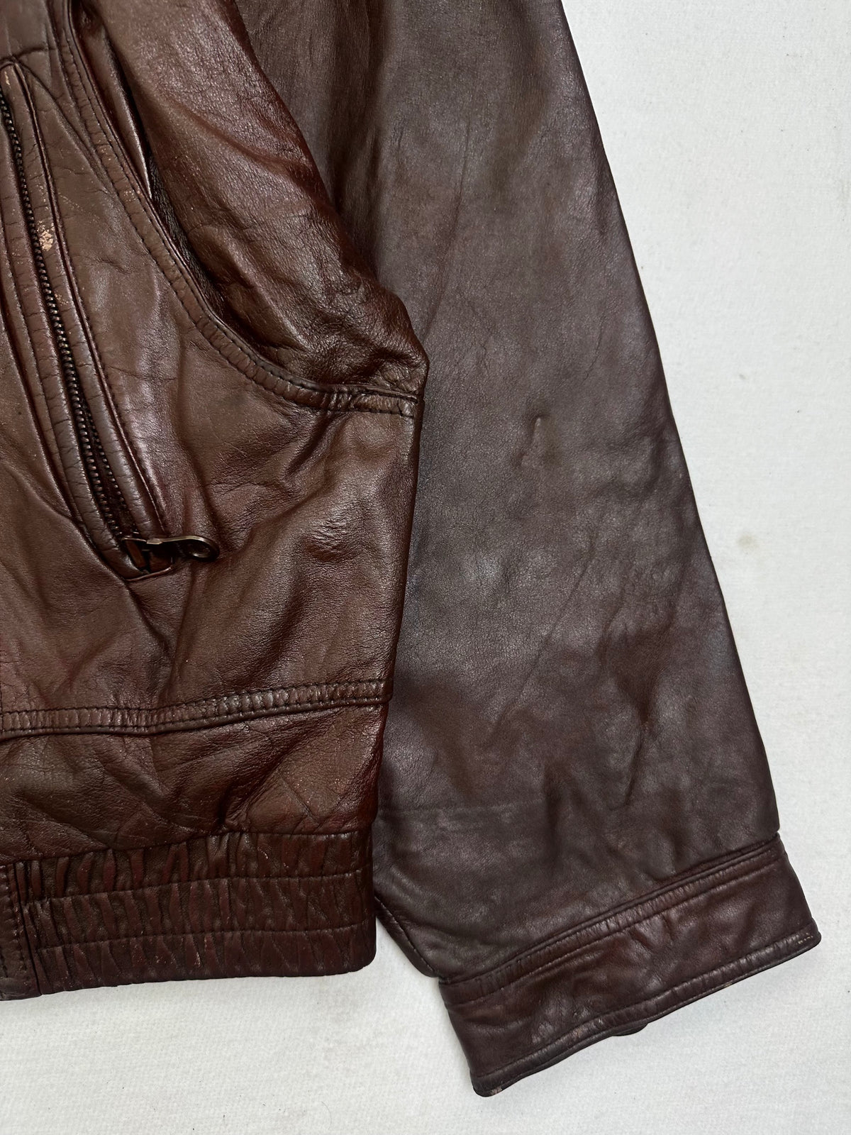 Side pocket and hem of the size L burgundy leather flight jacket, up close