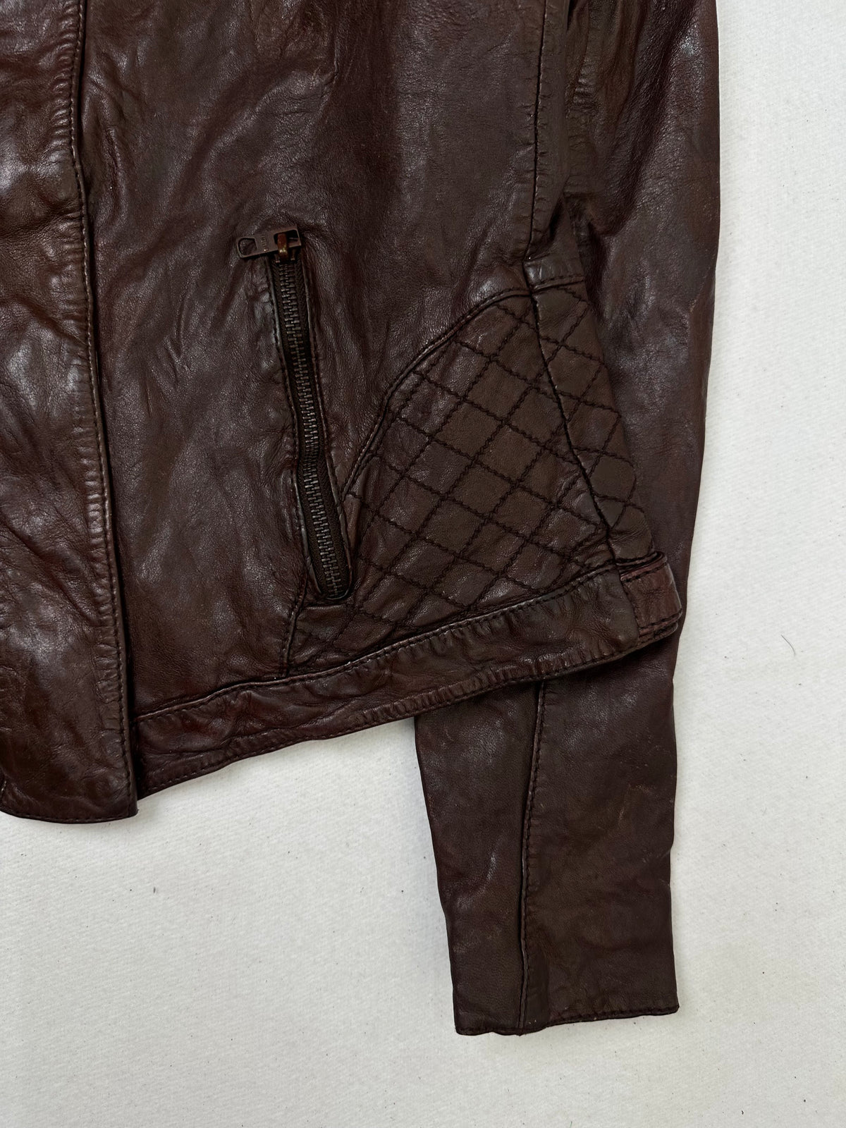 Side pocket and hem of the size S burgundy leather vintage jacket, up close