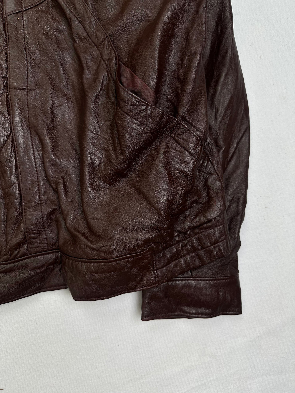 Side pocket and hem of the size L burgundy leather vintage jacket, up close