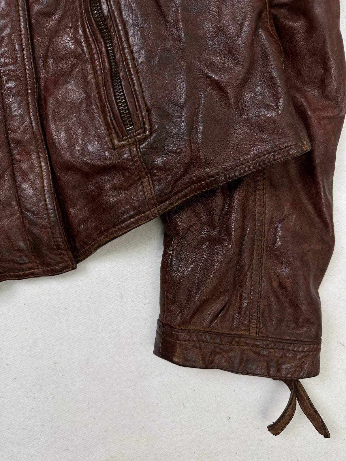 Side pocket and hem of the size S burgundy leather biker jacket, up close