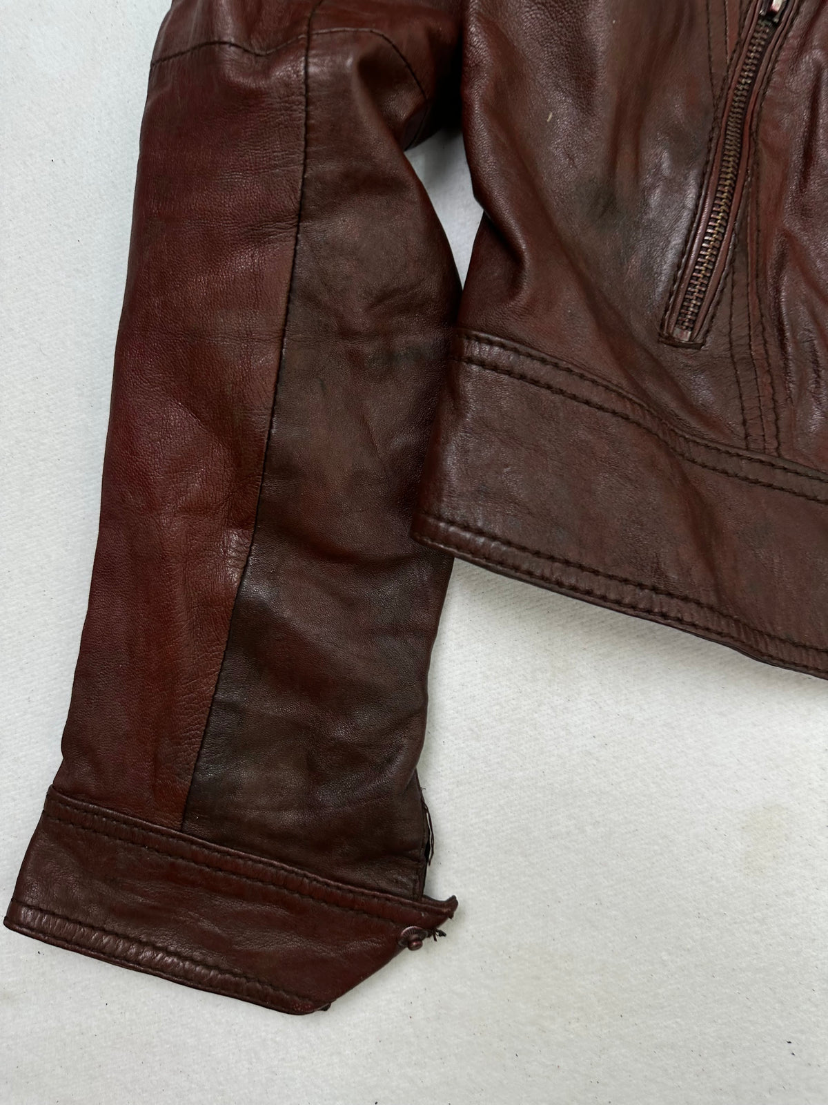 Close detail of the pockets and cuff on the size S burgundy leather cafe racer jacket