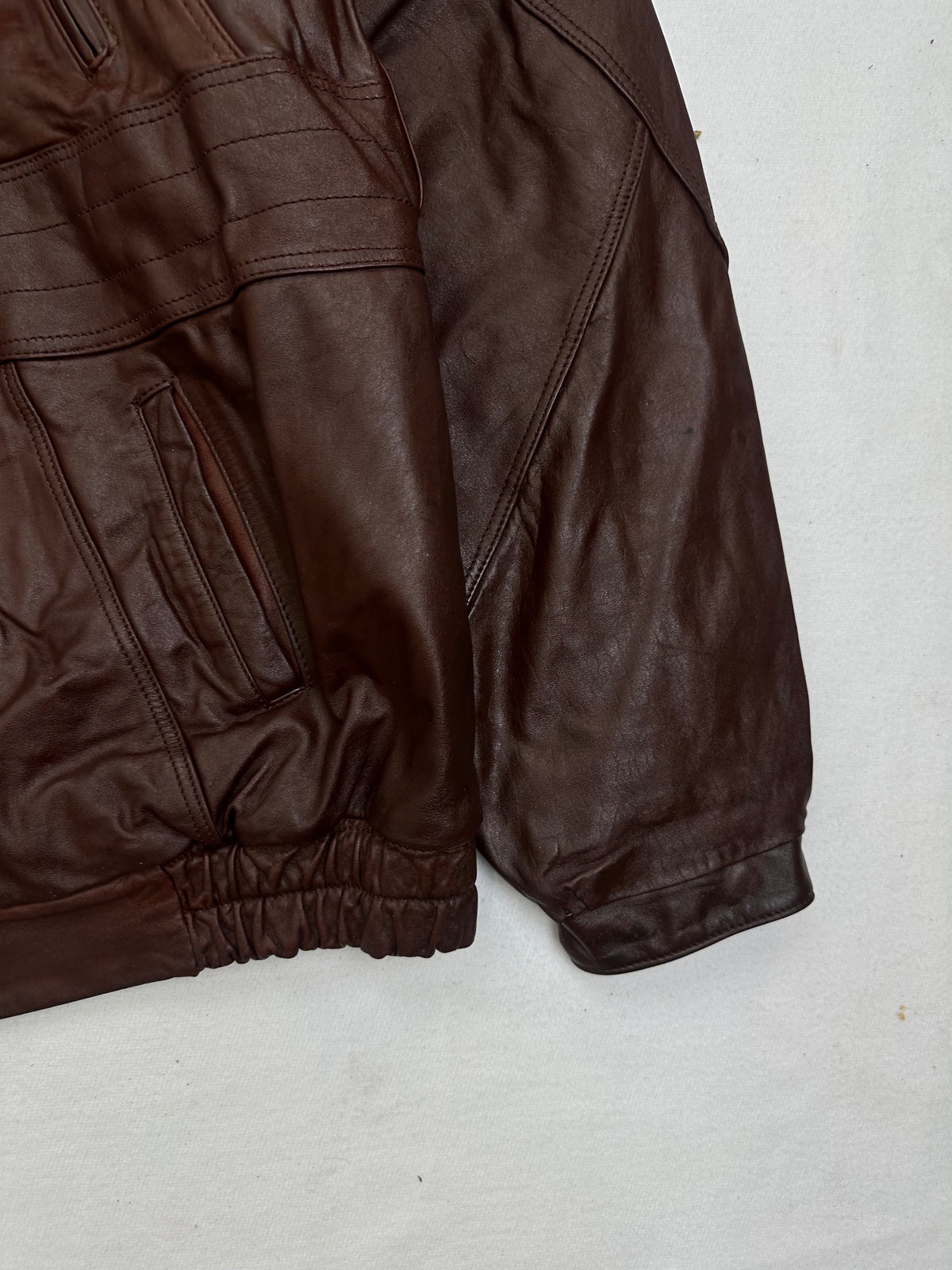 Side pocket and hem of the size L burgundy leather vintage jacket, up close