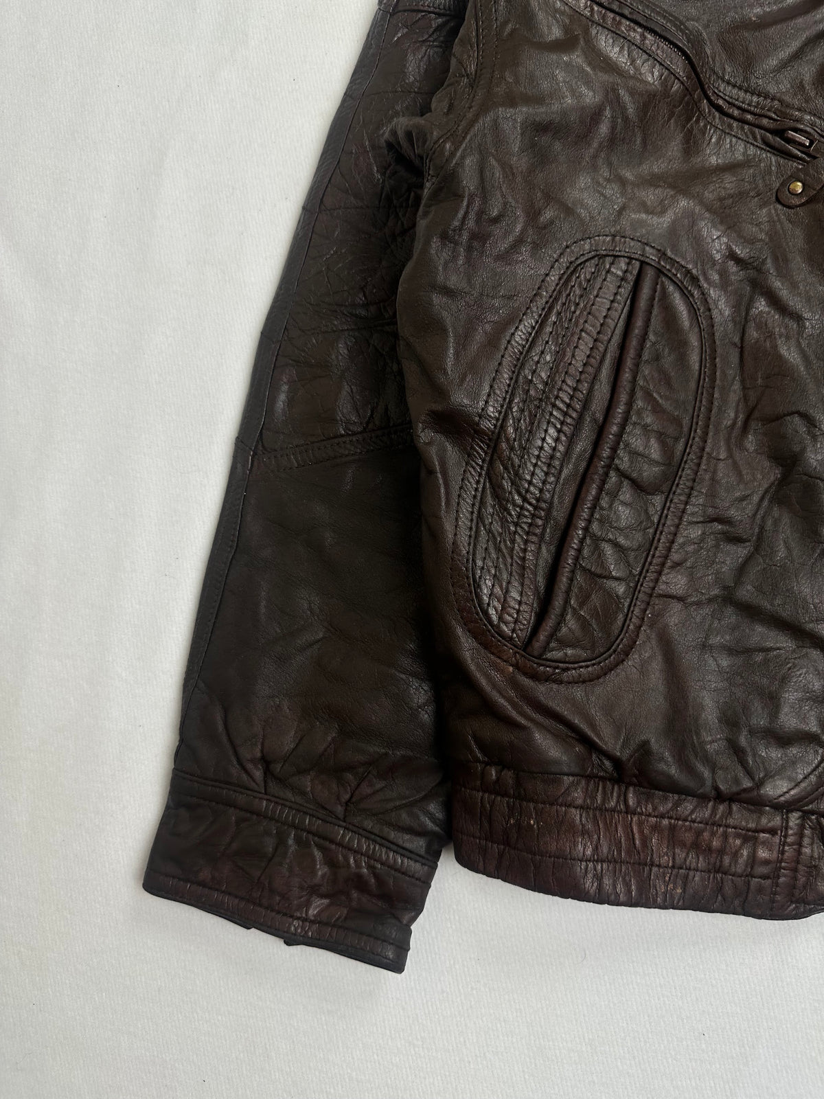 Quilted oval panel framing a lower slash pocket on the brown jacket