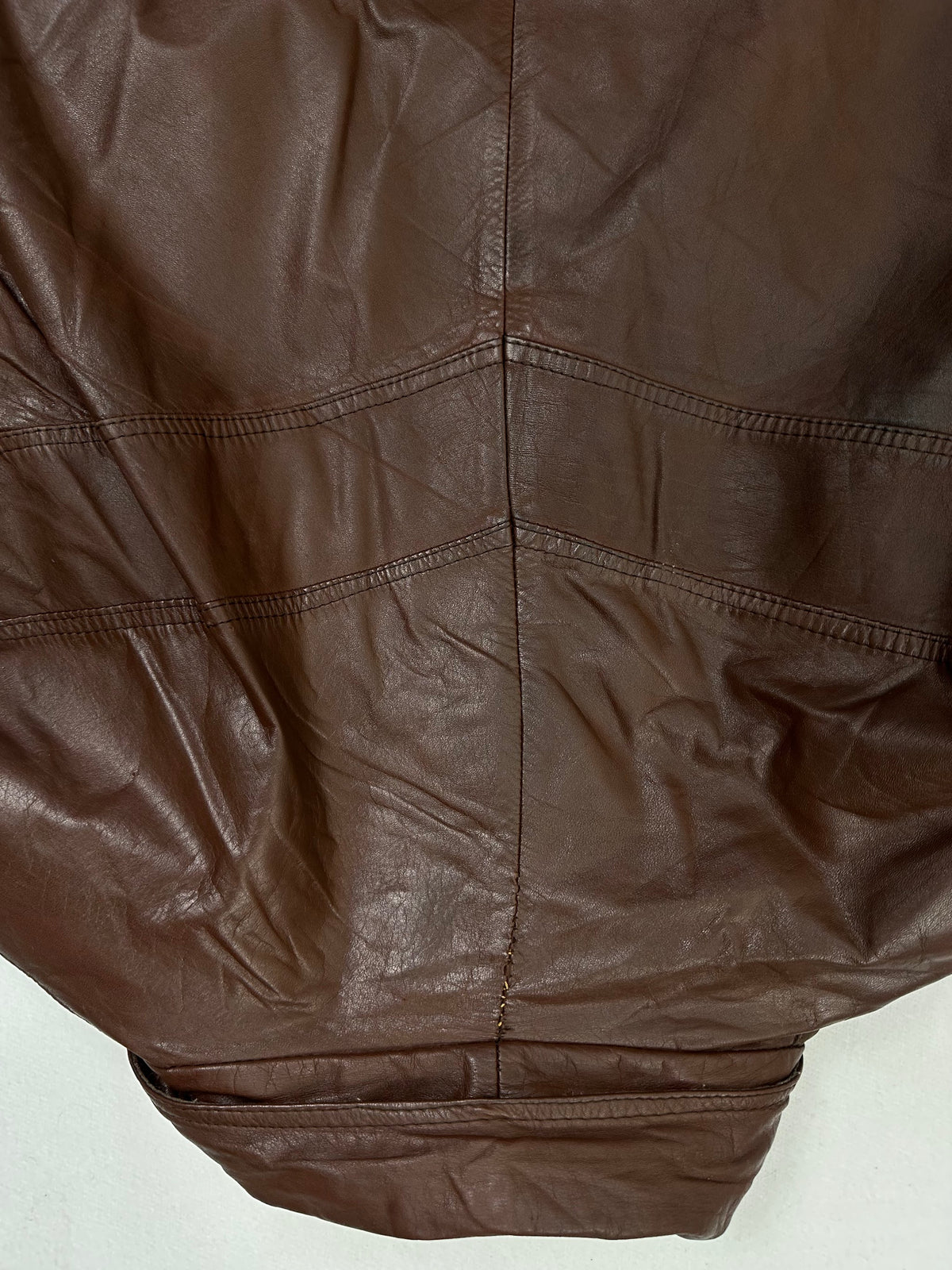 Panel seams and hem band on the size XL burgundy leather vintage jacket, up close