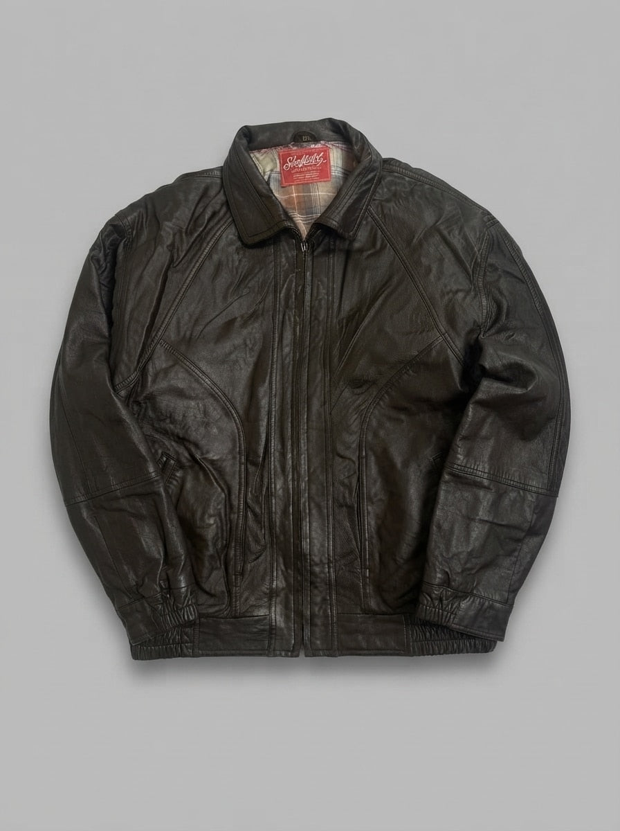 Dark brown leather harrington jacket laid flat, pointed collar, straight centre zip and shirred leather waistband