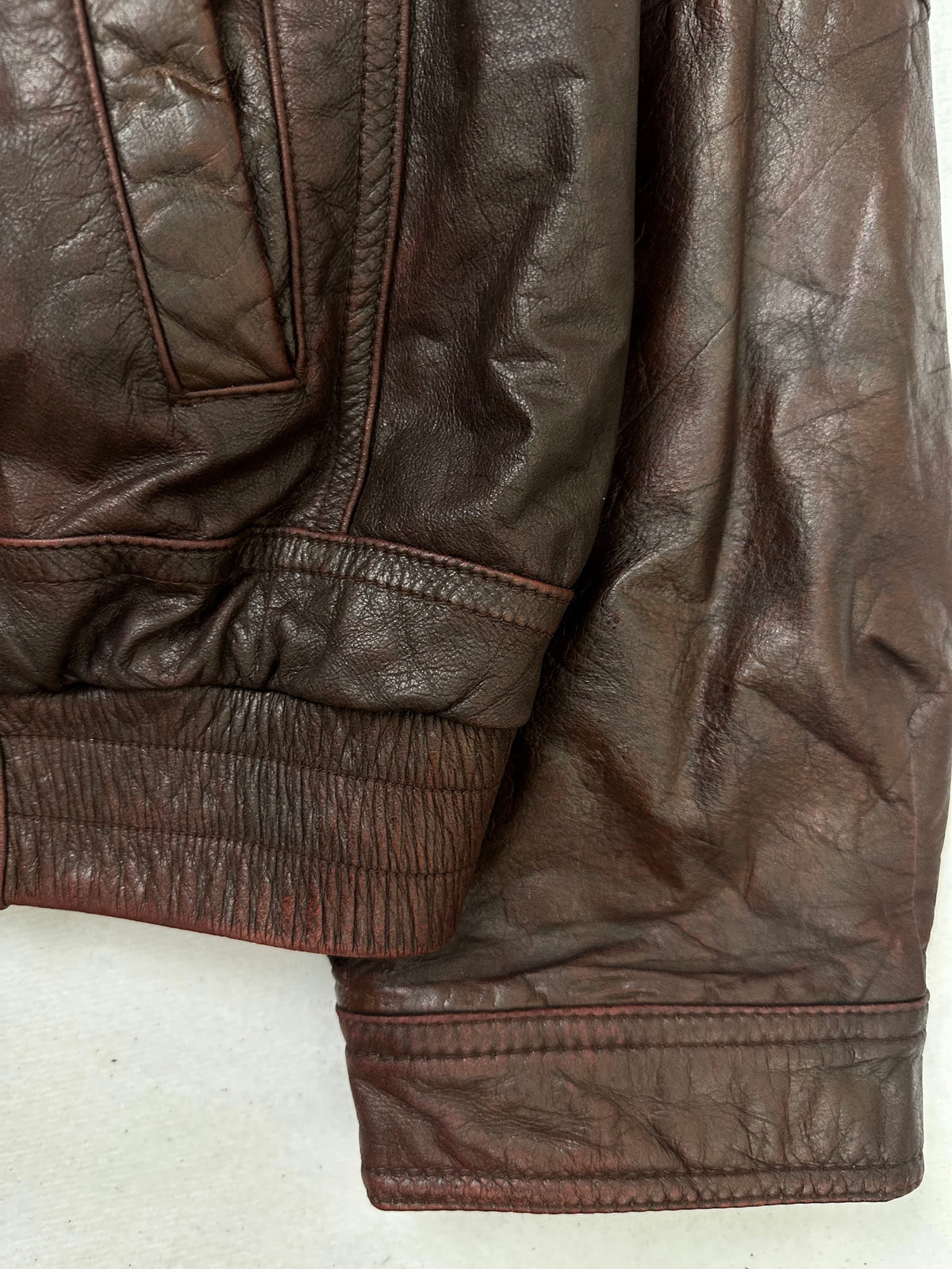 Side pocket and hem of the size L burgundy leather flight jacket, up close