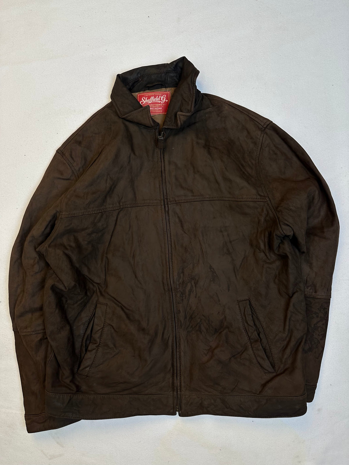 Front of the size XL brown leather vintage jacket, laid flat and unedited