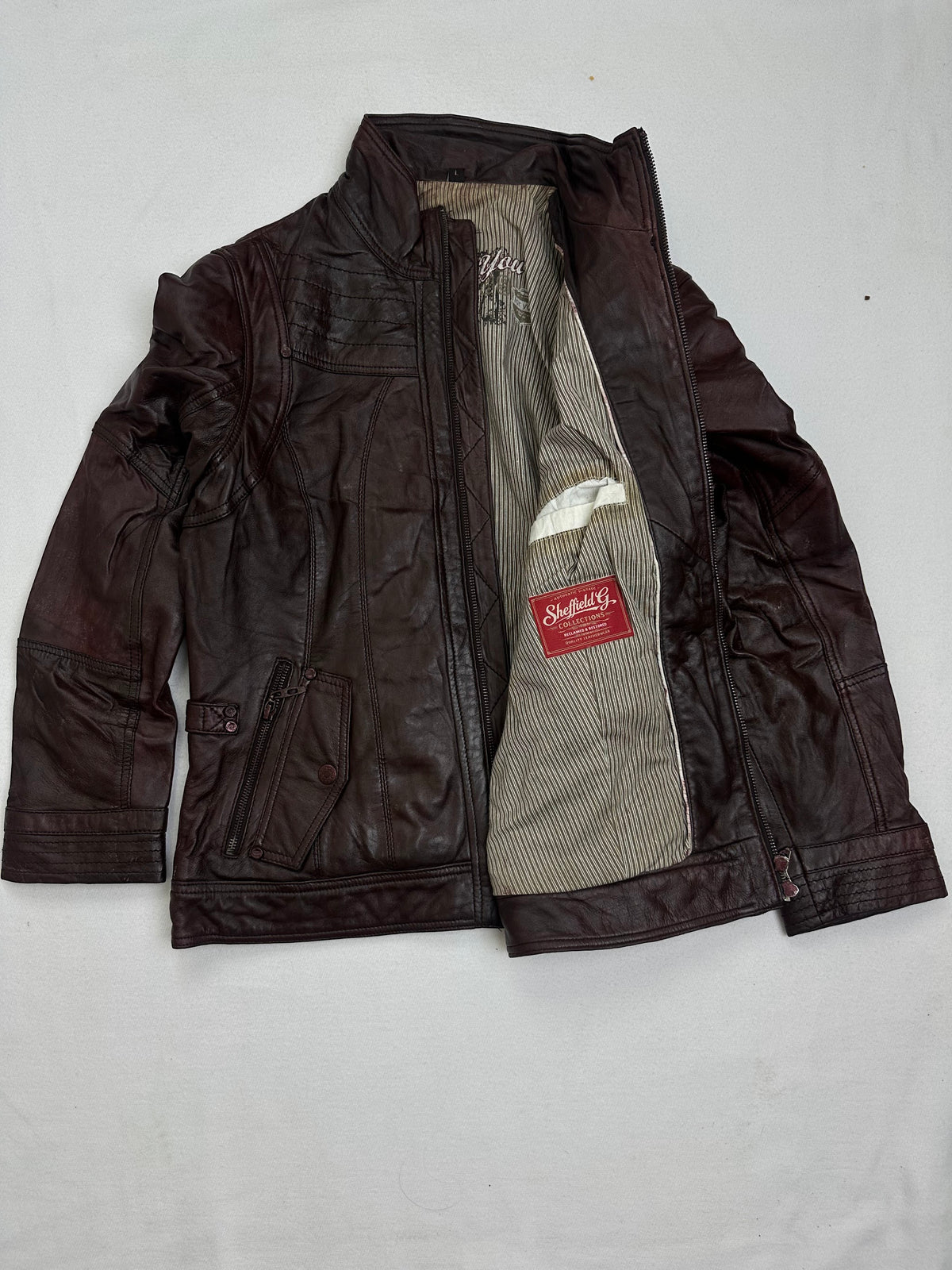 The size M burgundy leather cafe racer jacket opened to show the lining