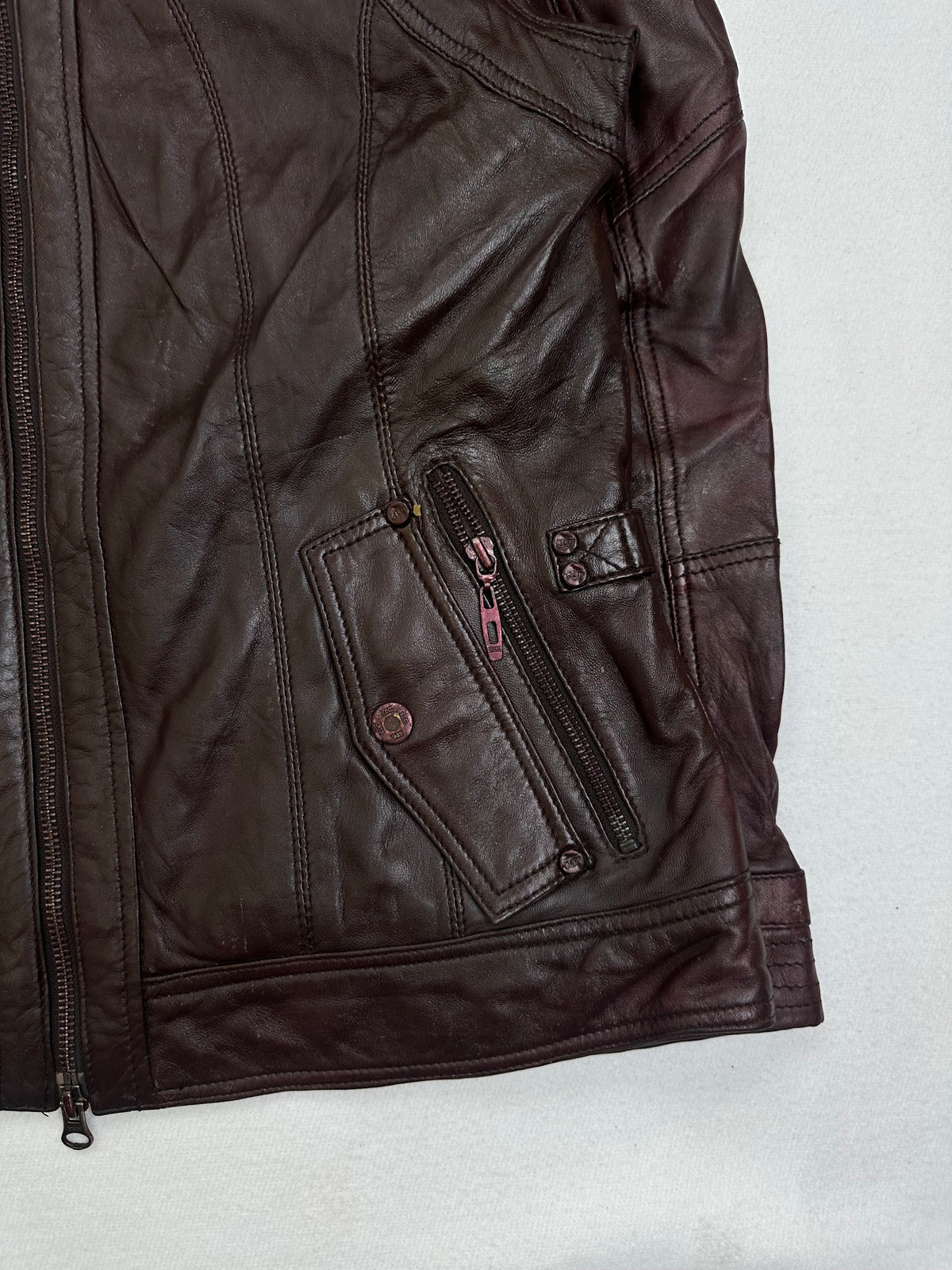 Side pocket and hem of the size M burgundy leather cafe racer jacket, up close