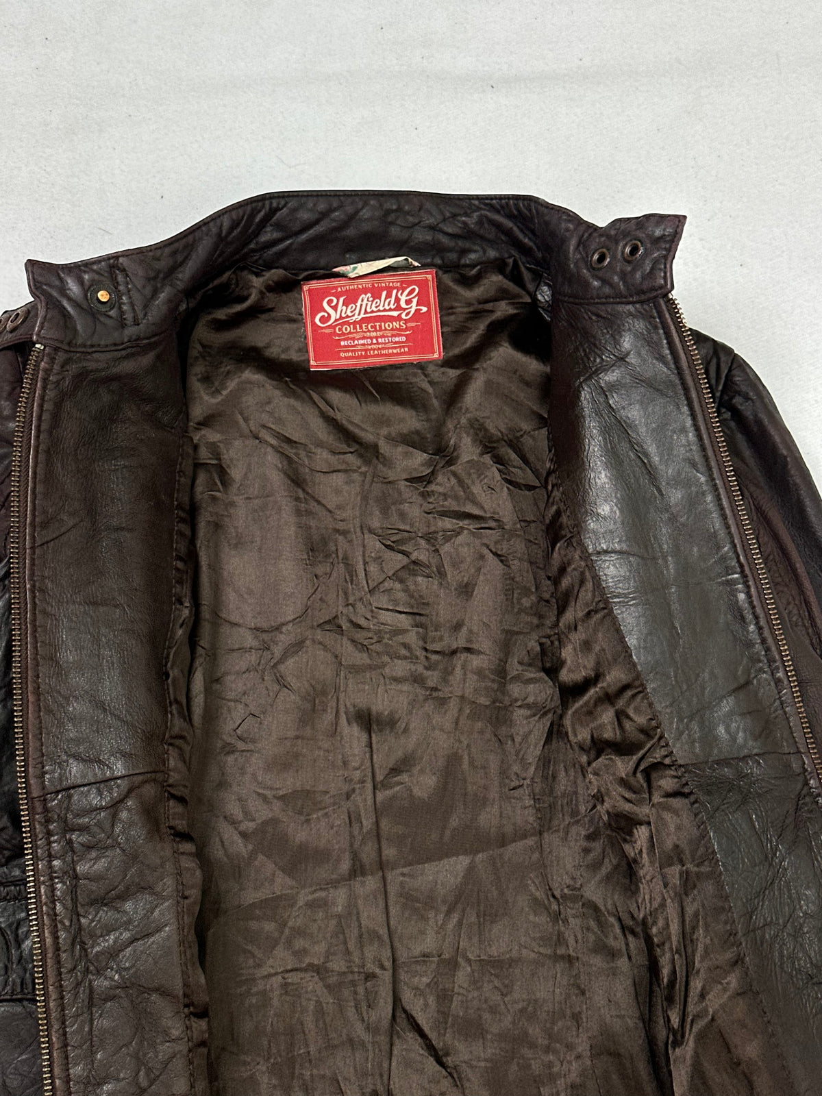 The size XS brown leather cafe racer jacket opened to show the lining
