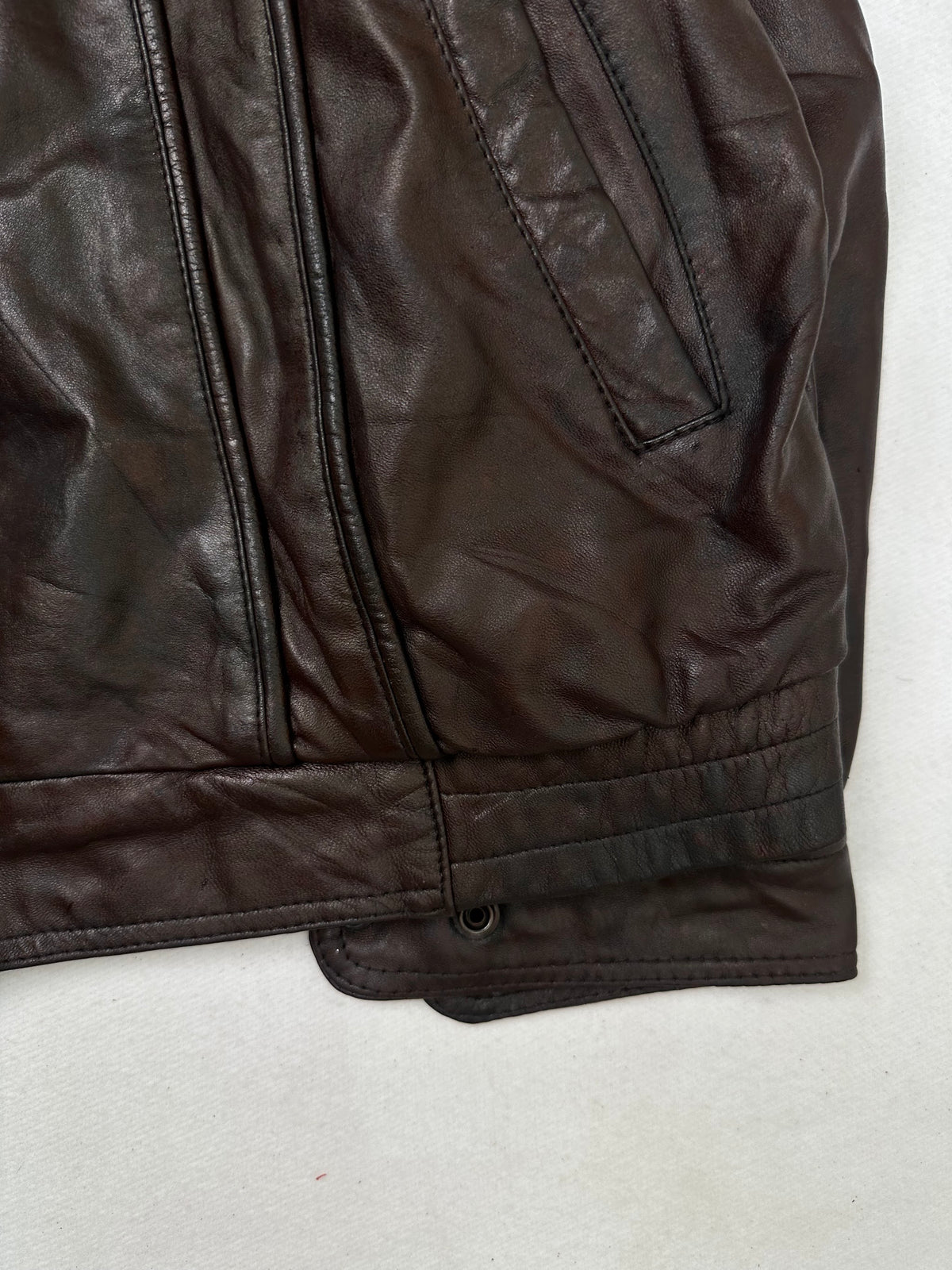 Side pocket and hem of the size L burgundy leather cafe racer jacket, up close