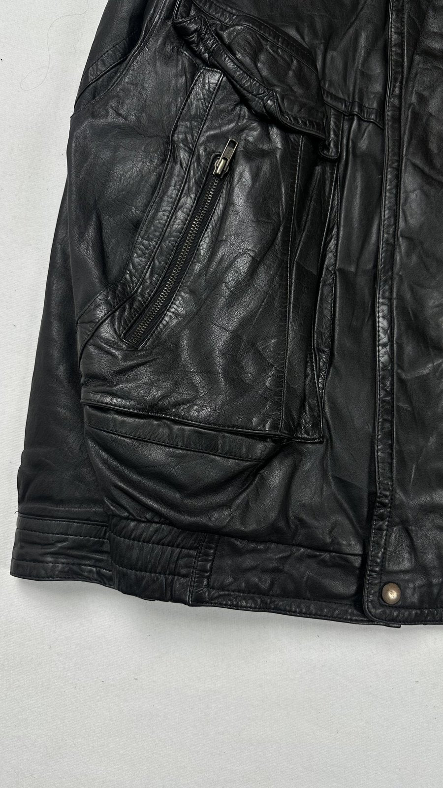 Lower front detail with a zipped pocket above a flap pocket and the gathered waist
