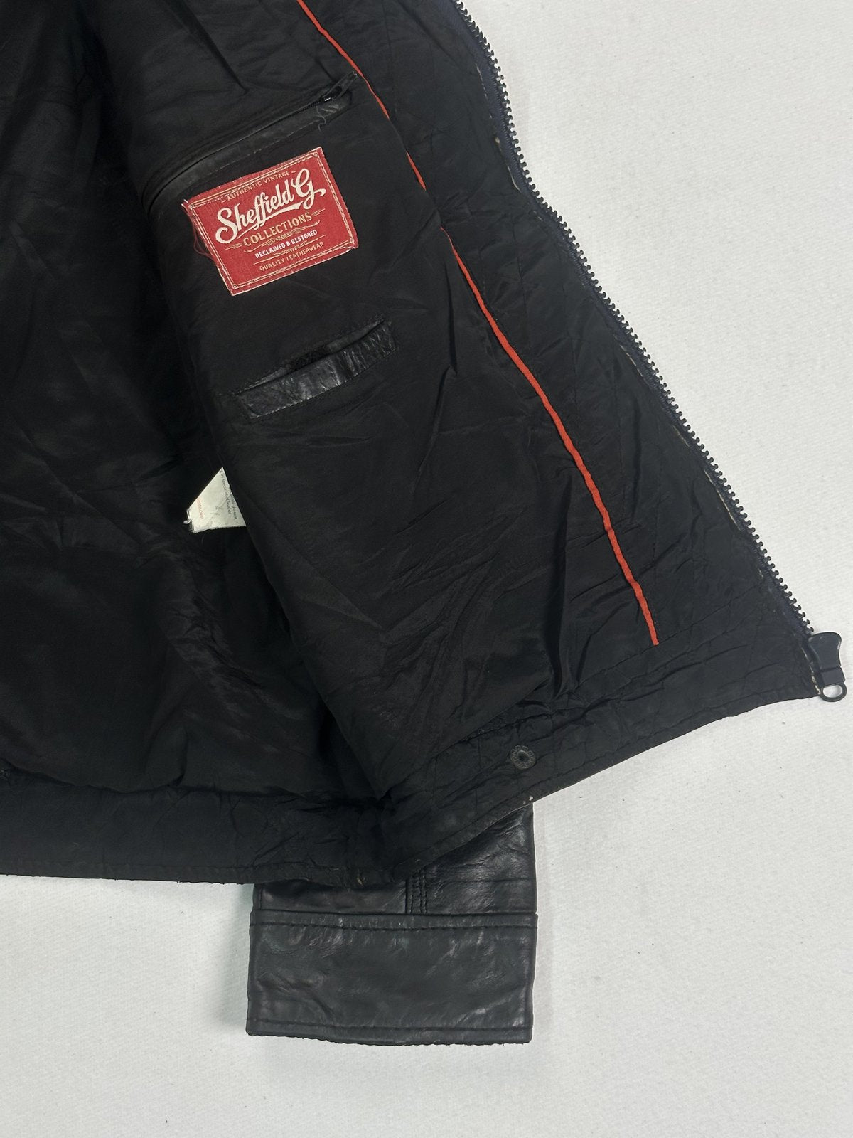 Inner pocket and red piping on the black lining of the moto cut jacket