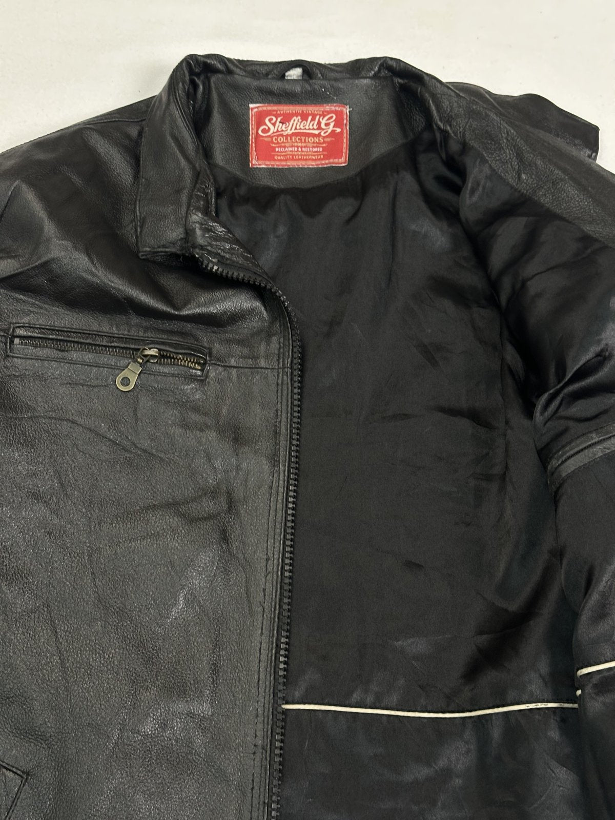 Neck and smooth dark lining seen inside the opened black leather jacket
