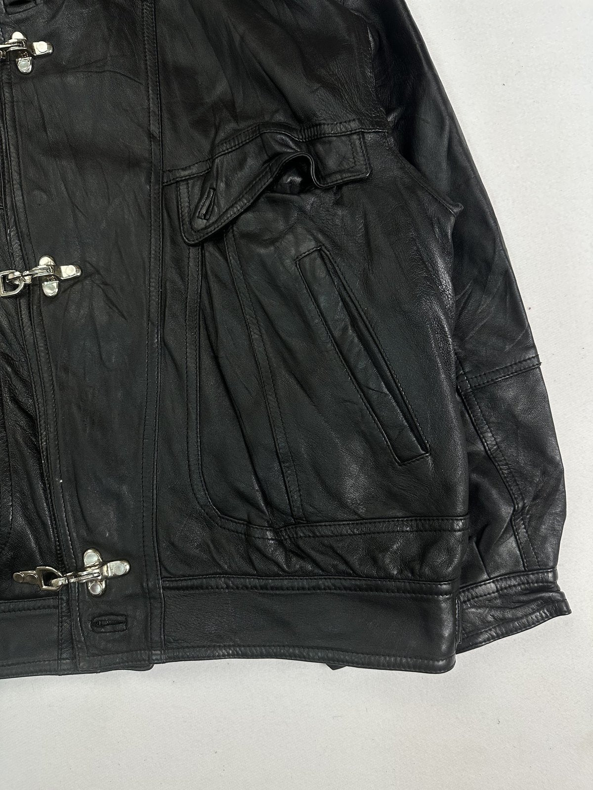 Angled view of a flap chest pocket and a welt hand pocket on the black leather