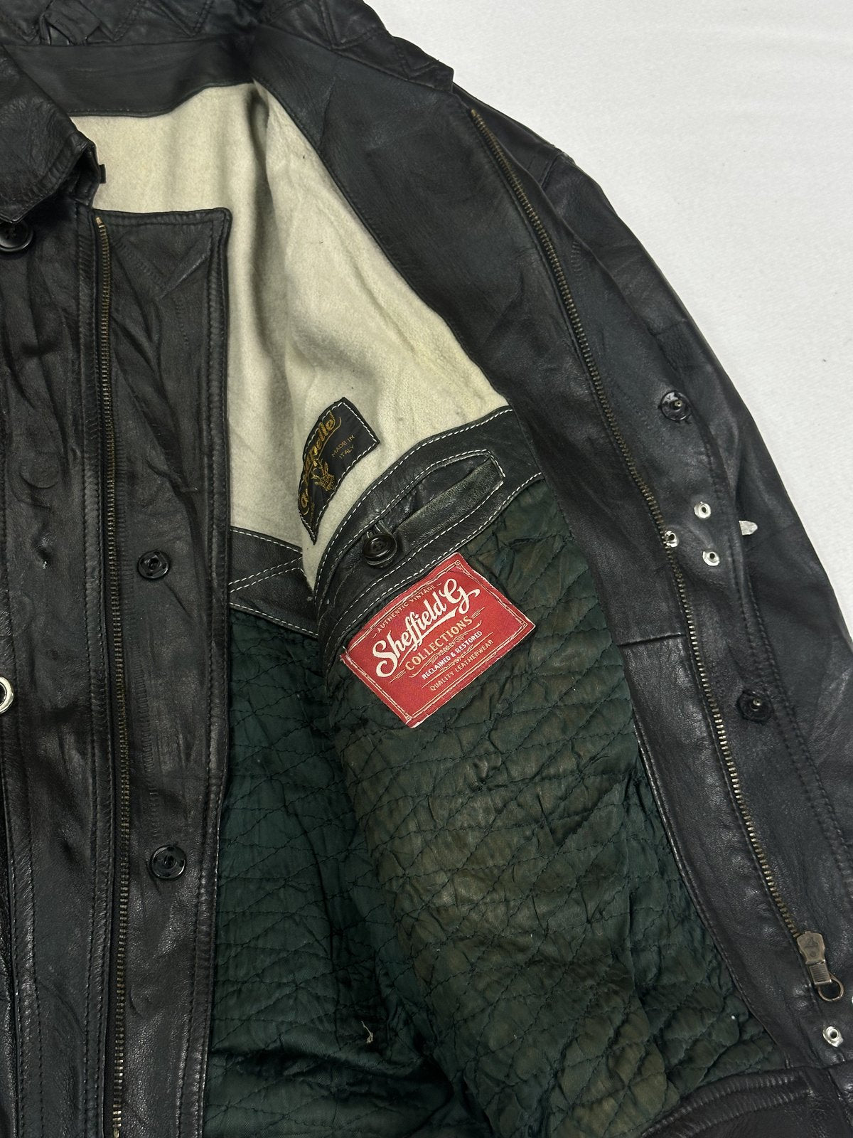 Close view of the green quilted lining and press studs inside the black jacket