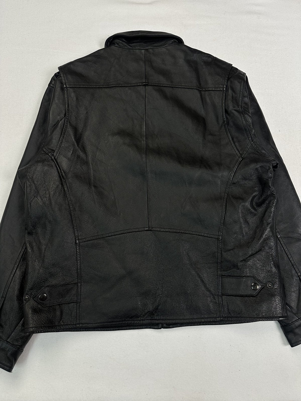 Back of the size L black jacket laid flat, showing the full leather panel and shoulder yoke