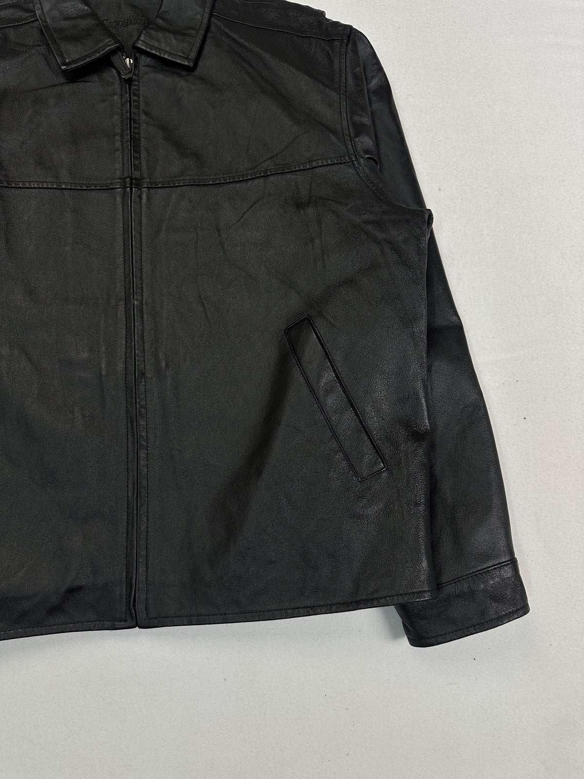 Angled view of the front zip, right hand pocket and cuff on this vintage black jacket