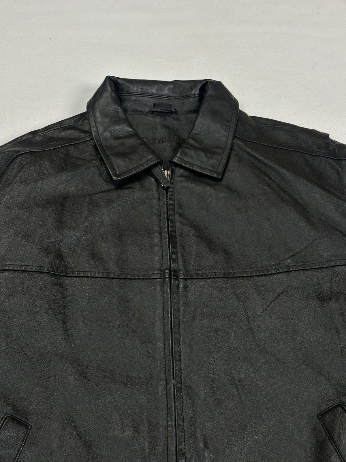 Close view of the pointed collar and the chest yoke seam running across the black leather