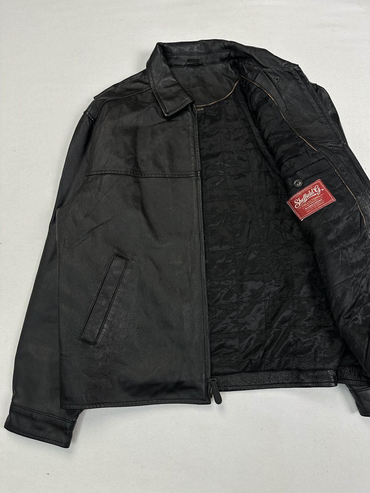 Quilted black lining inside the leather jacket, held open to show the interior