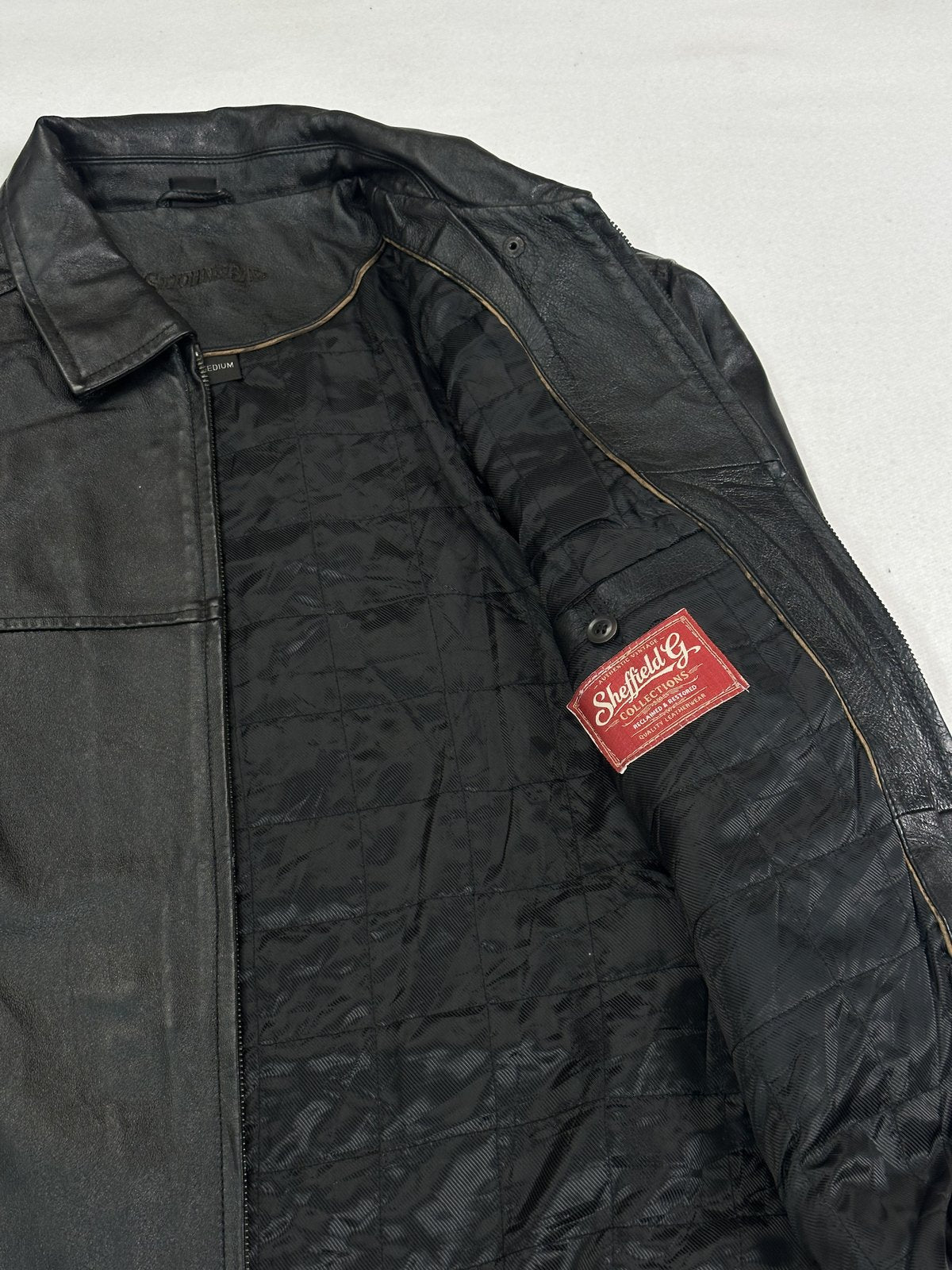 Detail of the red woven label stitched into the quilted lining of the black jacket