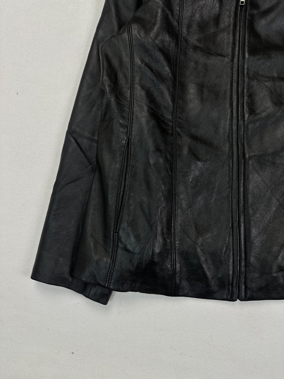 Lower left front of the black jacket with the centre zip running down to a straight hem