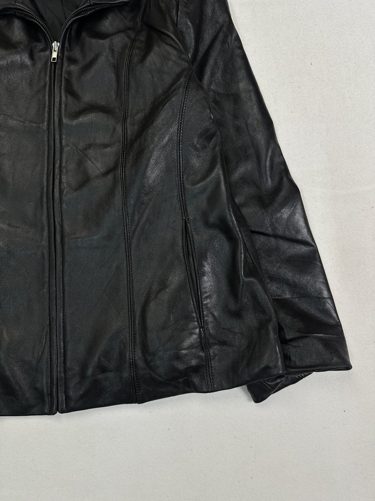 Angled view of the seam pocket, cuff and hem on this black leather cafe racer