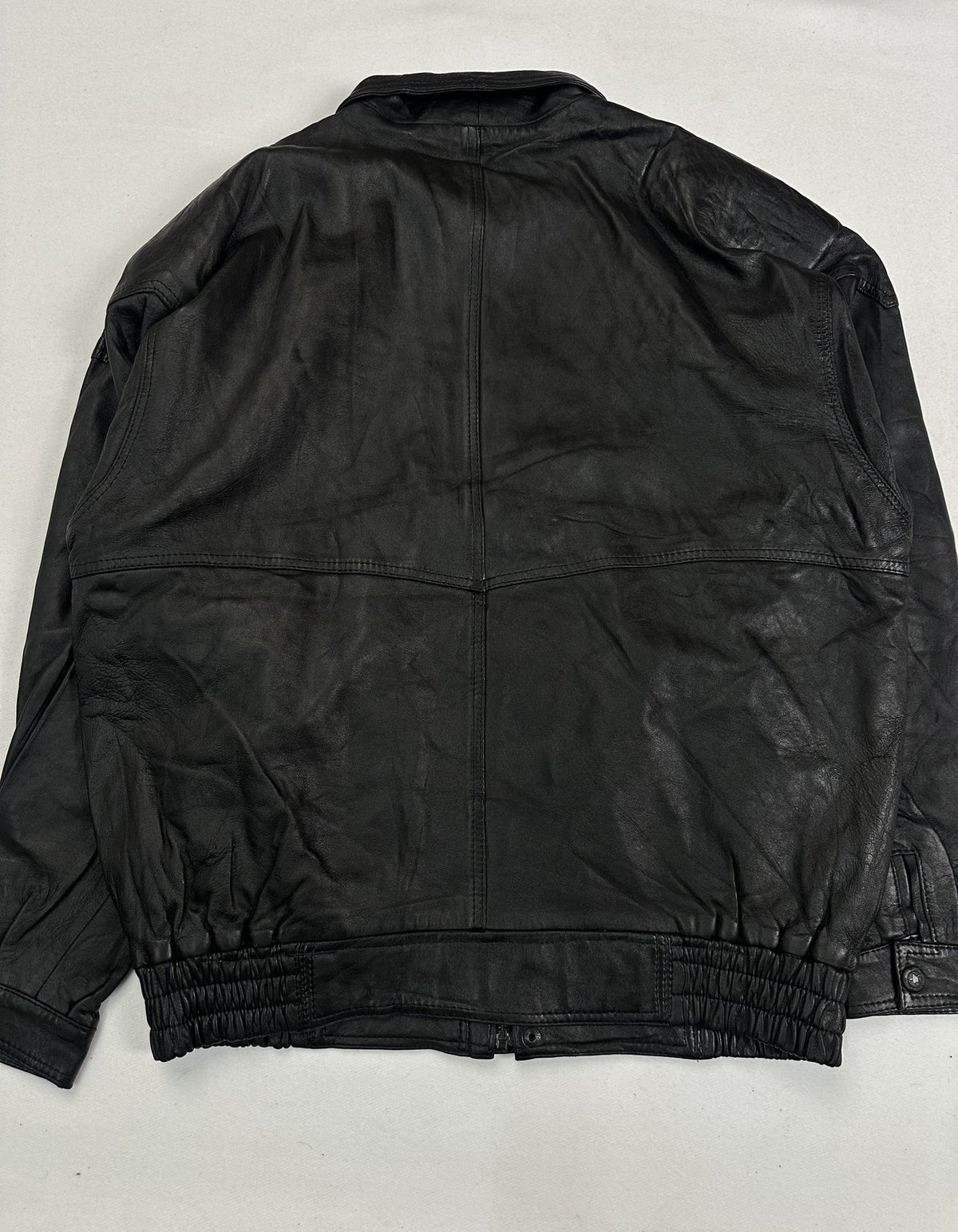 Storm flap covering the concealed zip on the black leather jacket