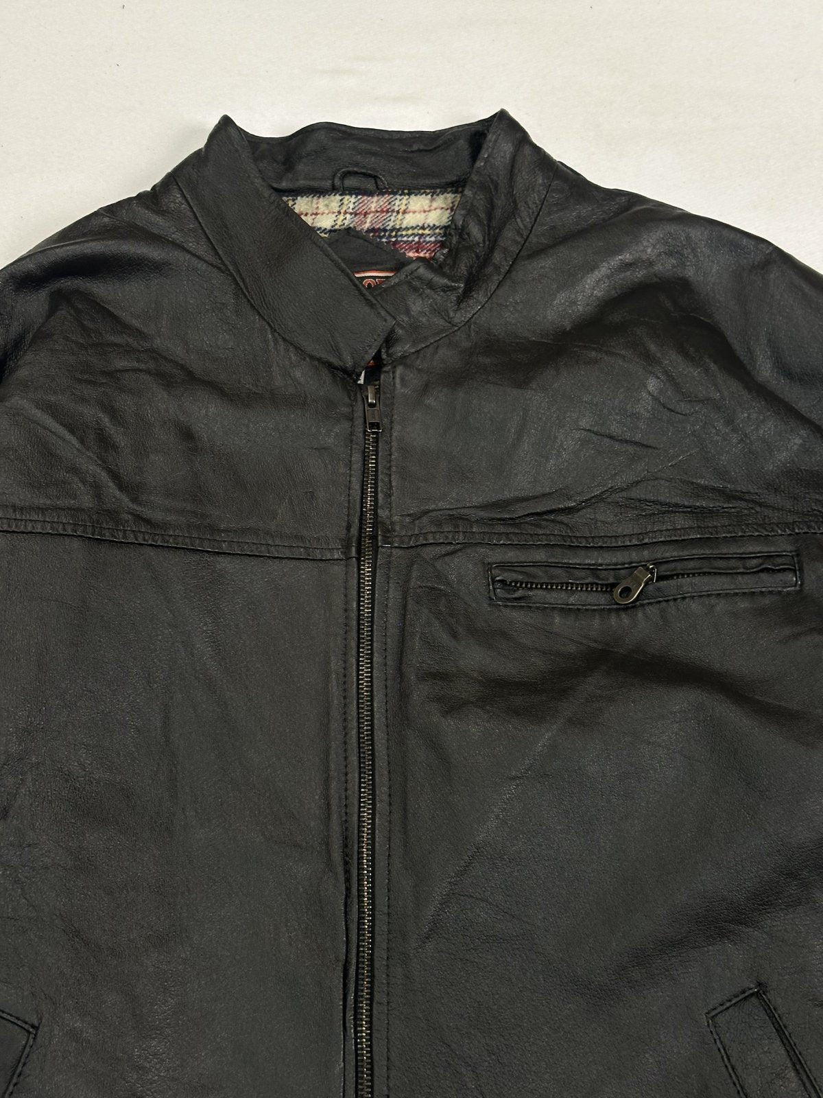 Close view of the ribbed band collar and the zip pull at the neck of the black Harrington