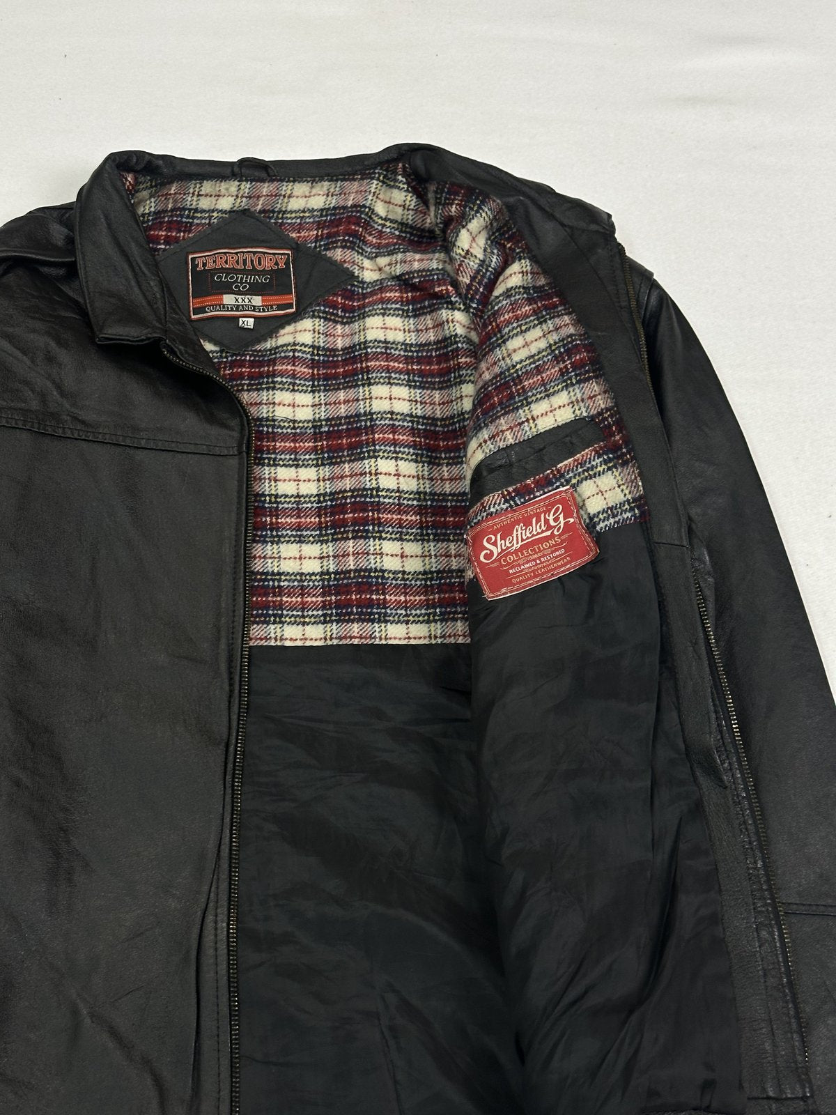 Cream and red plaid check lining at the shoulder inside the black leather jacket
