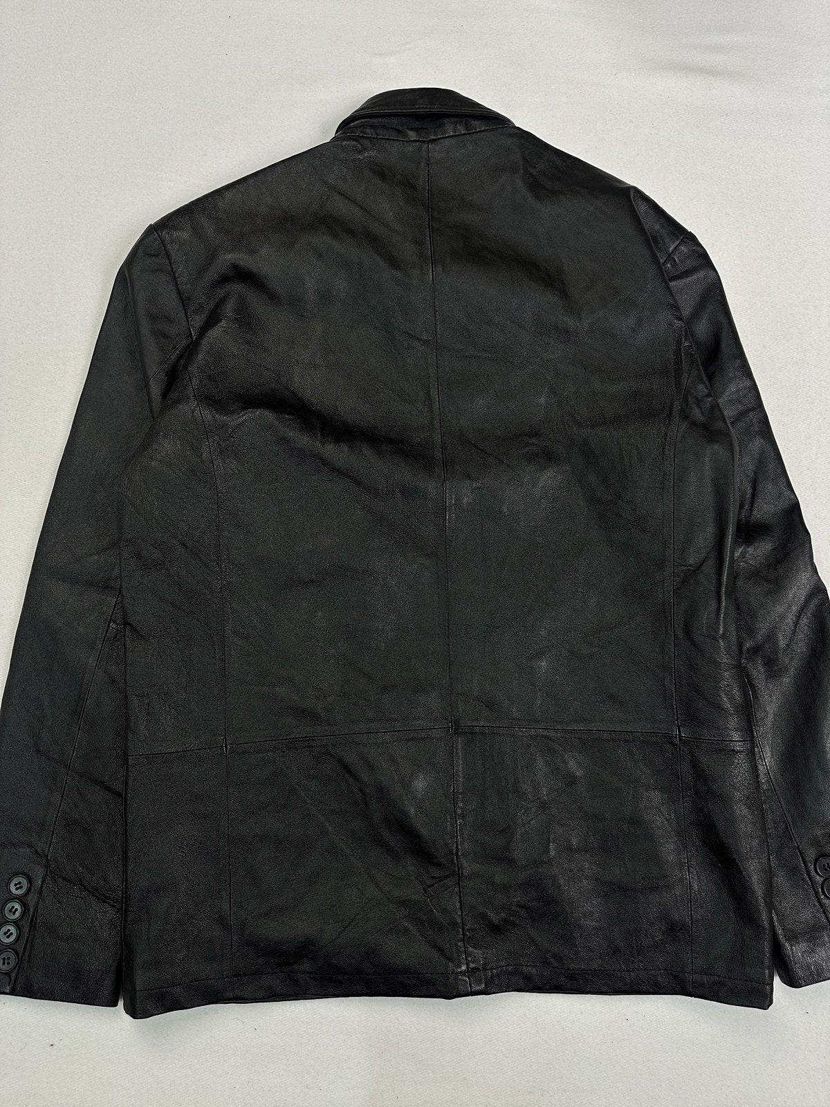 Back of the size L black jacket laid flat, showing the buttoned blazer-style cuffs