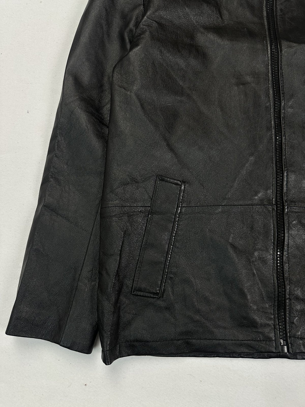 Lower front corner showing a welt hand pocket and the short vent at the side hem