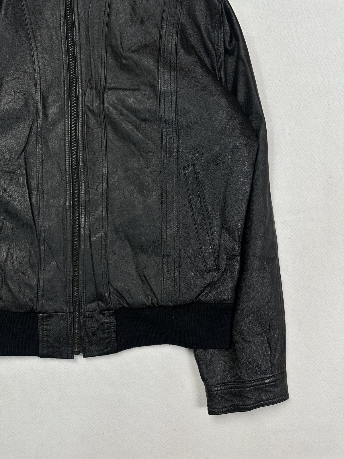 Close view of the front zip running into the rib hem beside the cuff