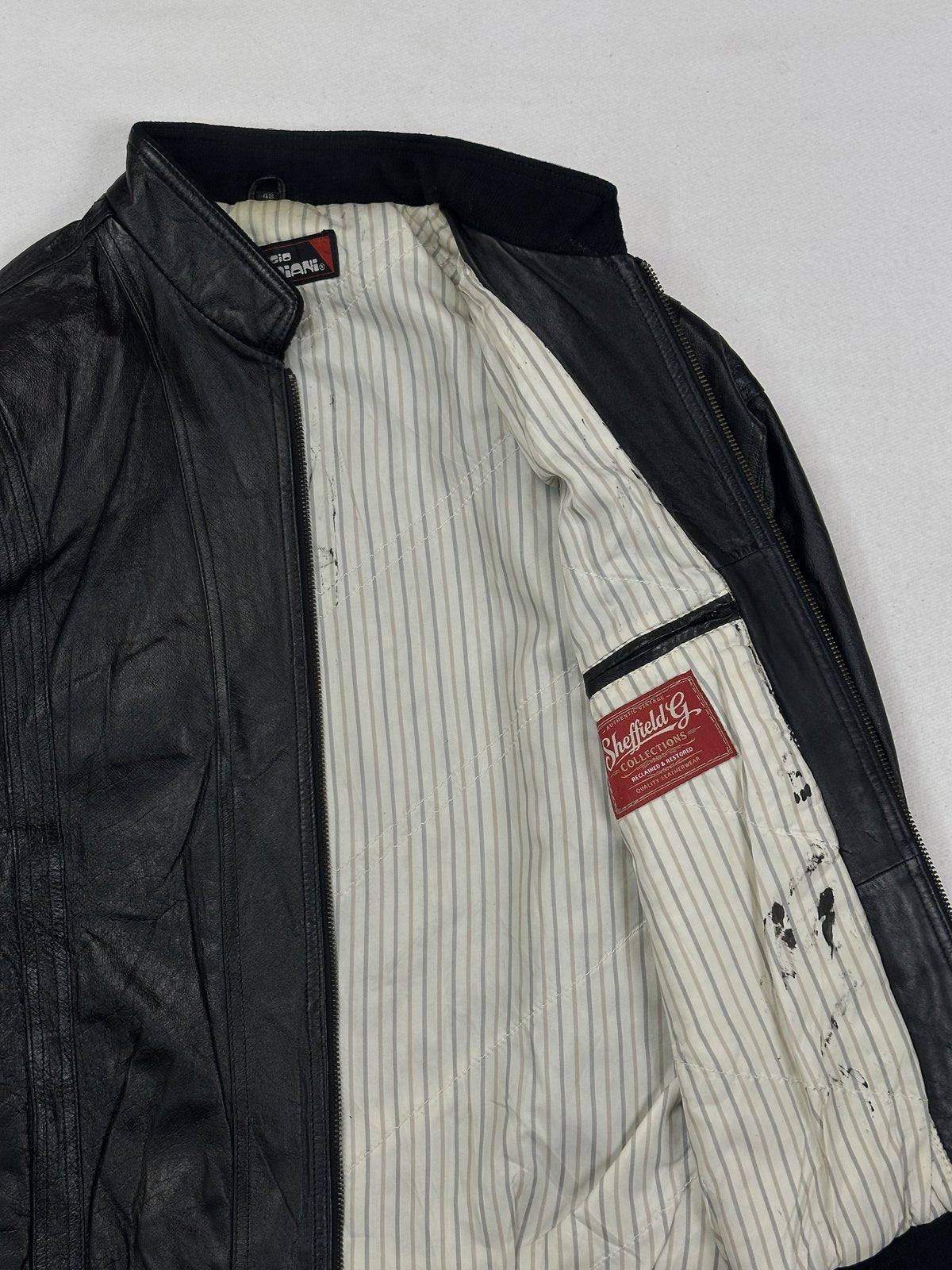 Cream pinstripe lining inside the black bomber, held open to show the interior