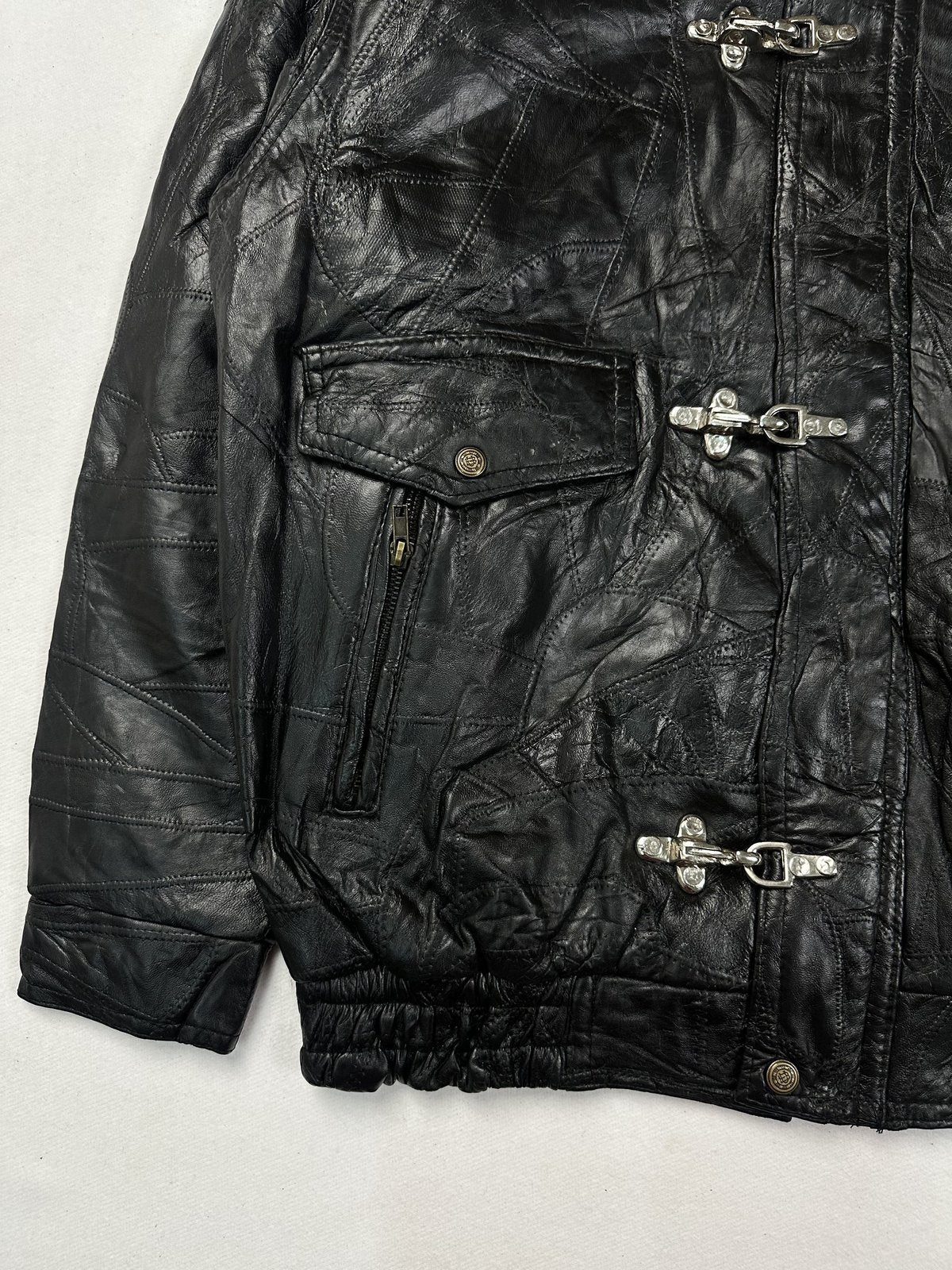 Toggle fastening on the front of the patchwork black leather jacket