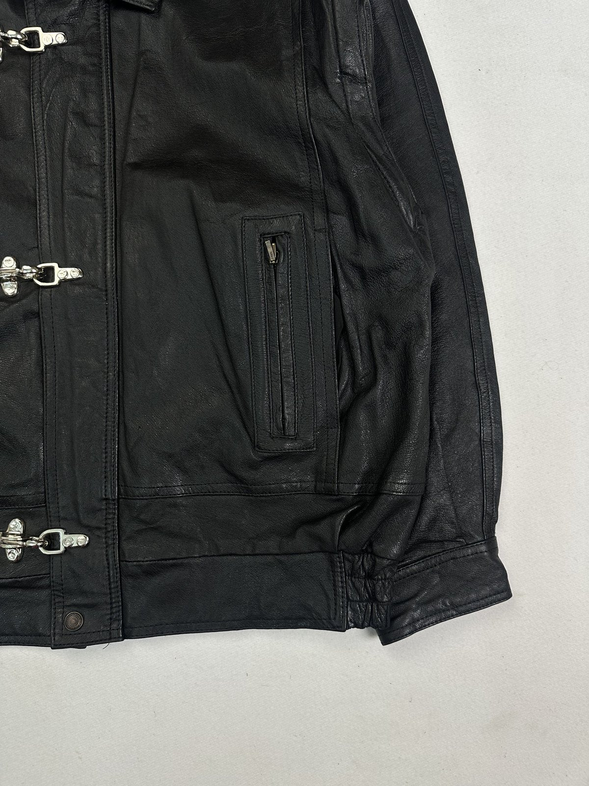 Angled detail of a slanted zip pocket and the gathered hem on the black leather