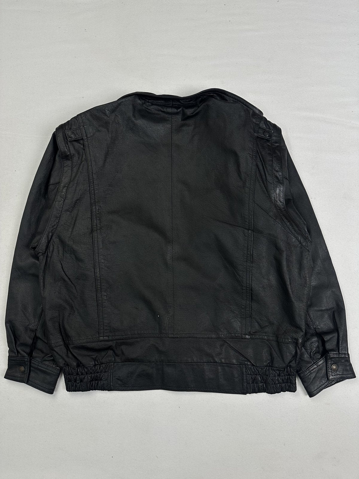 Back of the XL black leather jacket laid flat showing the plain panel and gathered hem