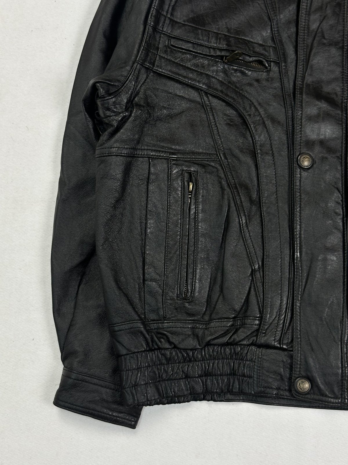 Lower front of the black bomber with a zip pocket and the gathered elasticated hem