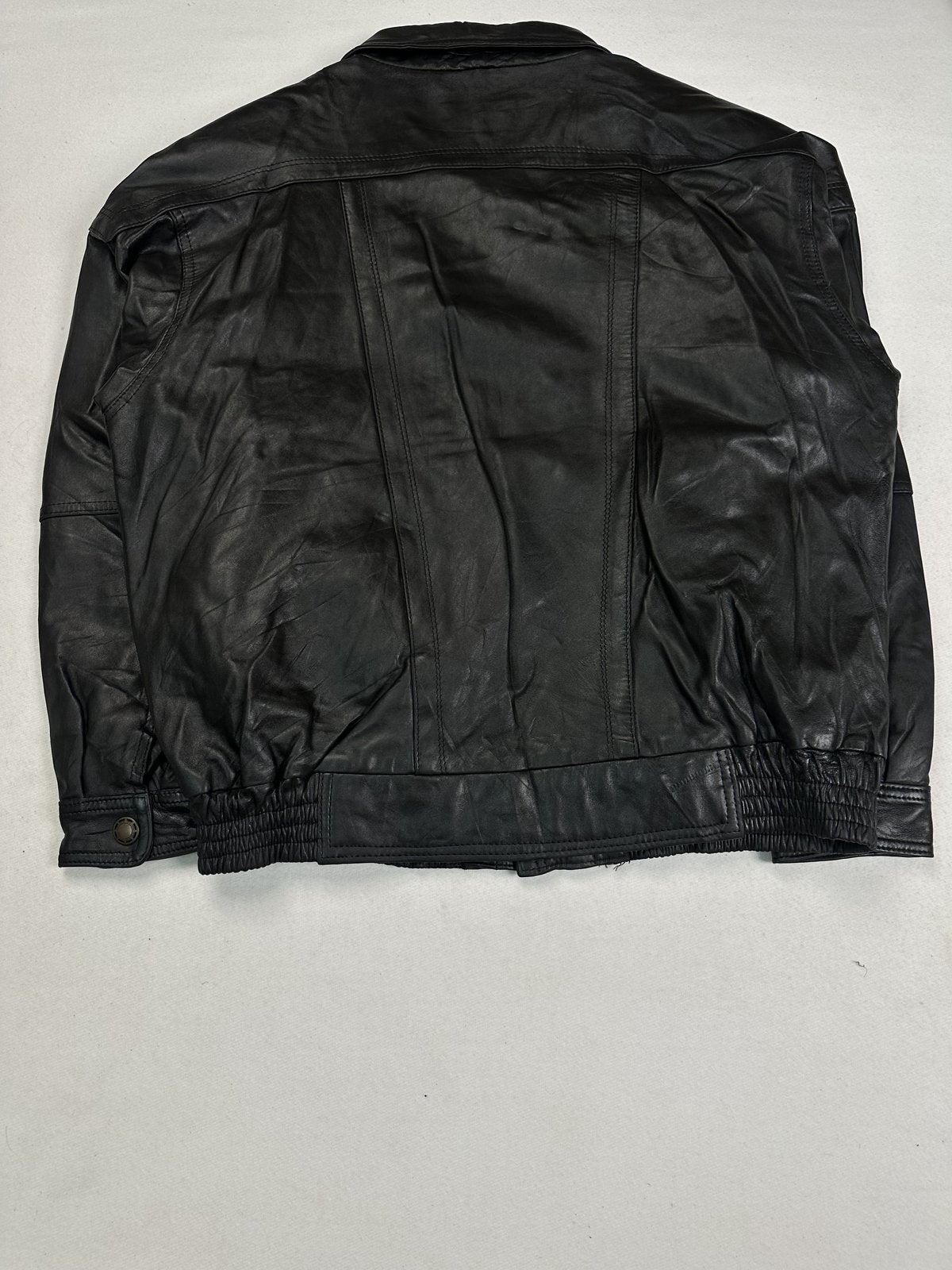 Back of the roomy XXL black bomber laid flat showing the yoke seam and elasticated hem