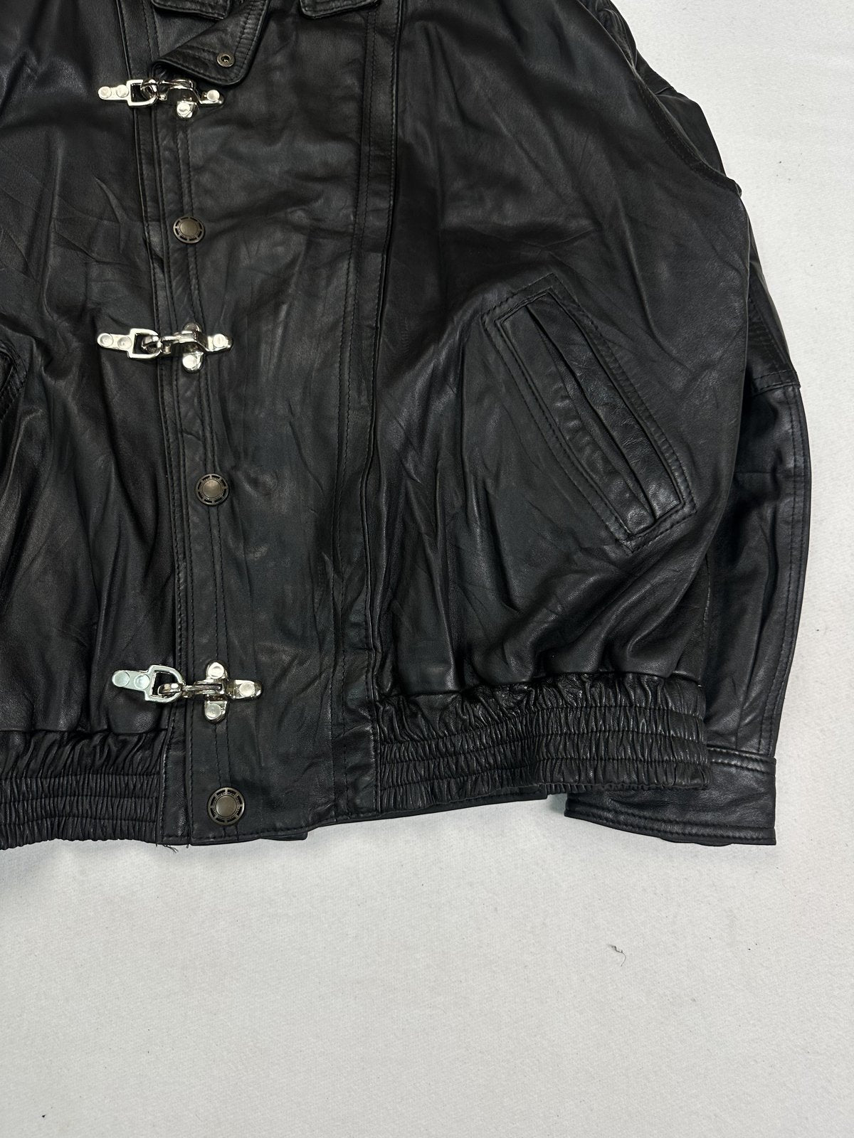 Angled view of the clasp fastenings and a leather flap pocket on the black bomber
