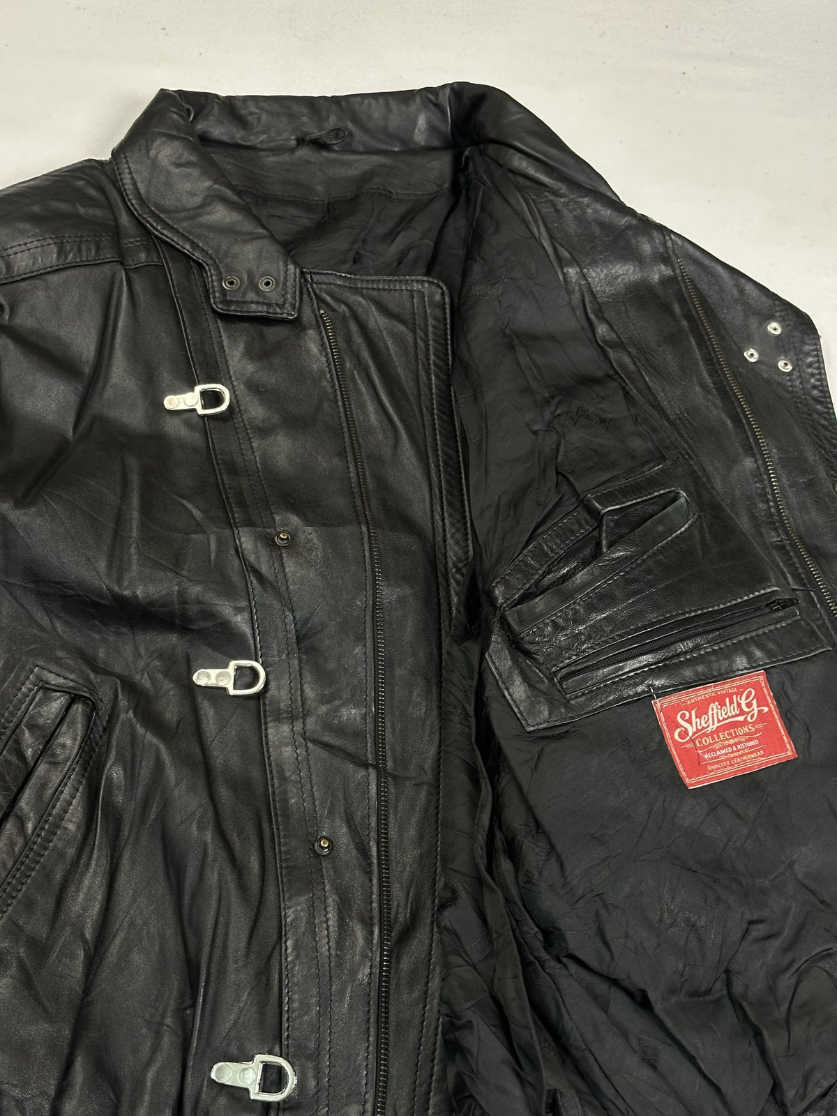 Detail of the inner pocket and press studs inside the opened black leather jacket