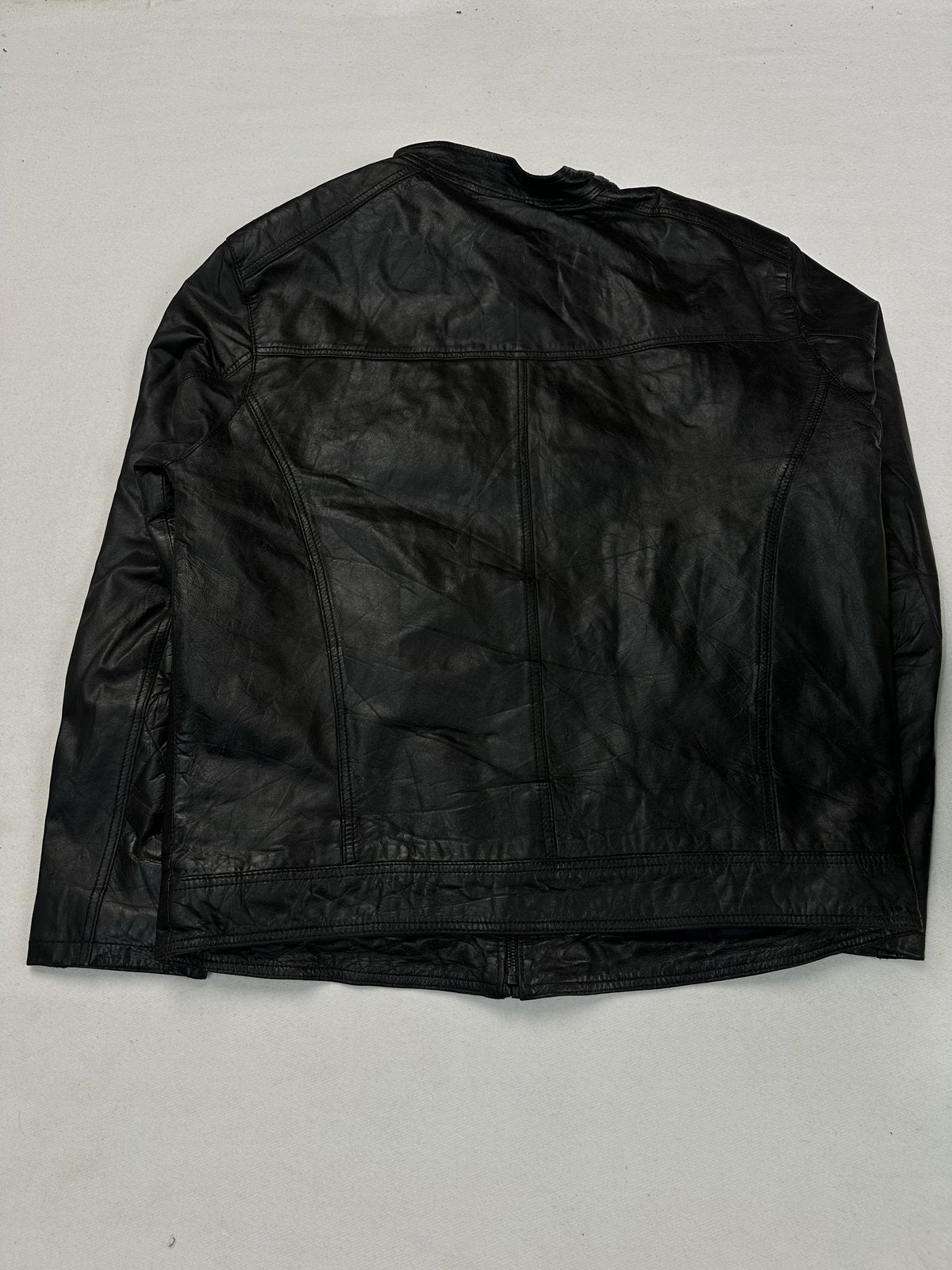 Back of the size L black jacket laid flat, showing the plain leather panel and side seams