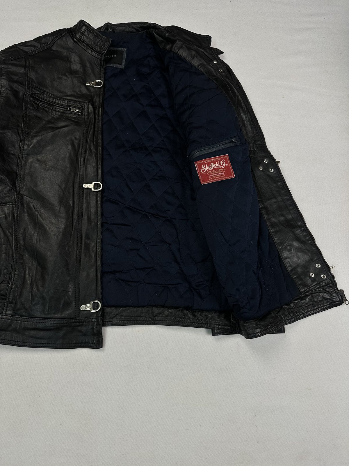 Navy quilted lining inside the black leather jacket, held open to show the interior
